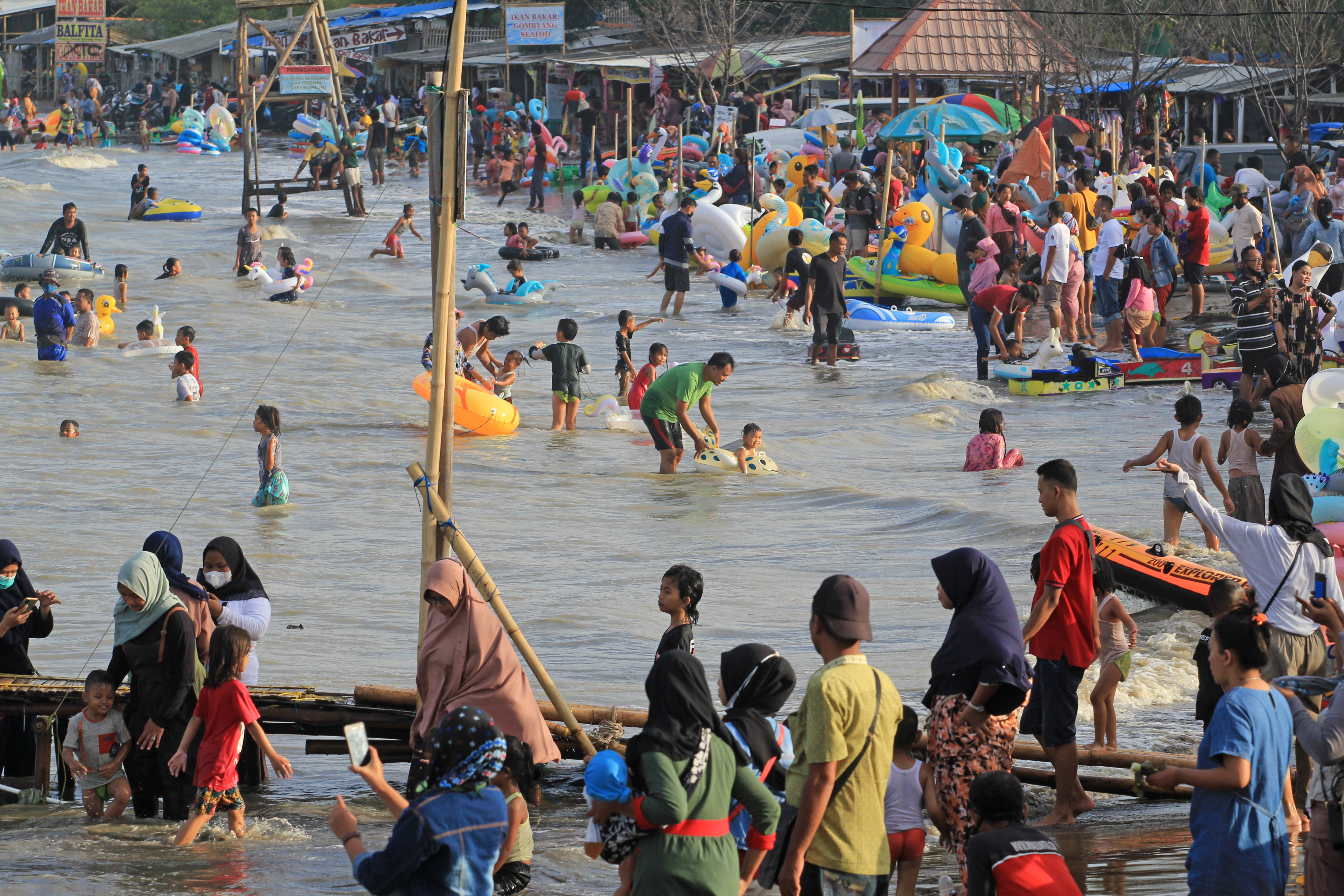 Pengunjung menikmati suasana liburan di pantai Karangsong, Indramayu, Jawa Barat, Jumat (14/5/2021)