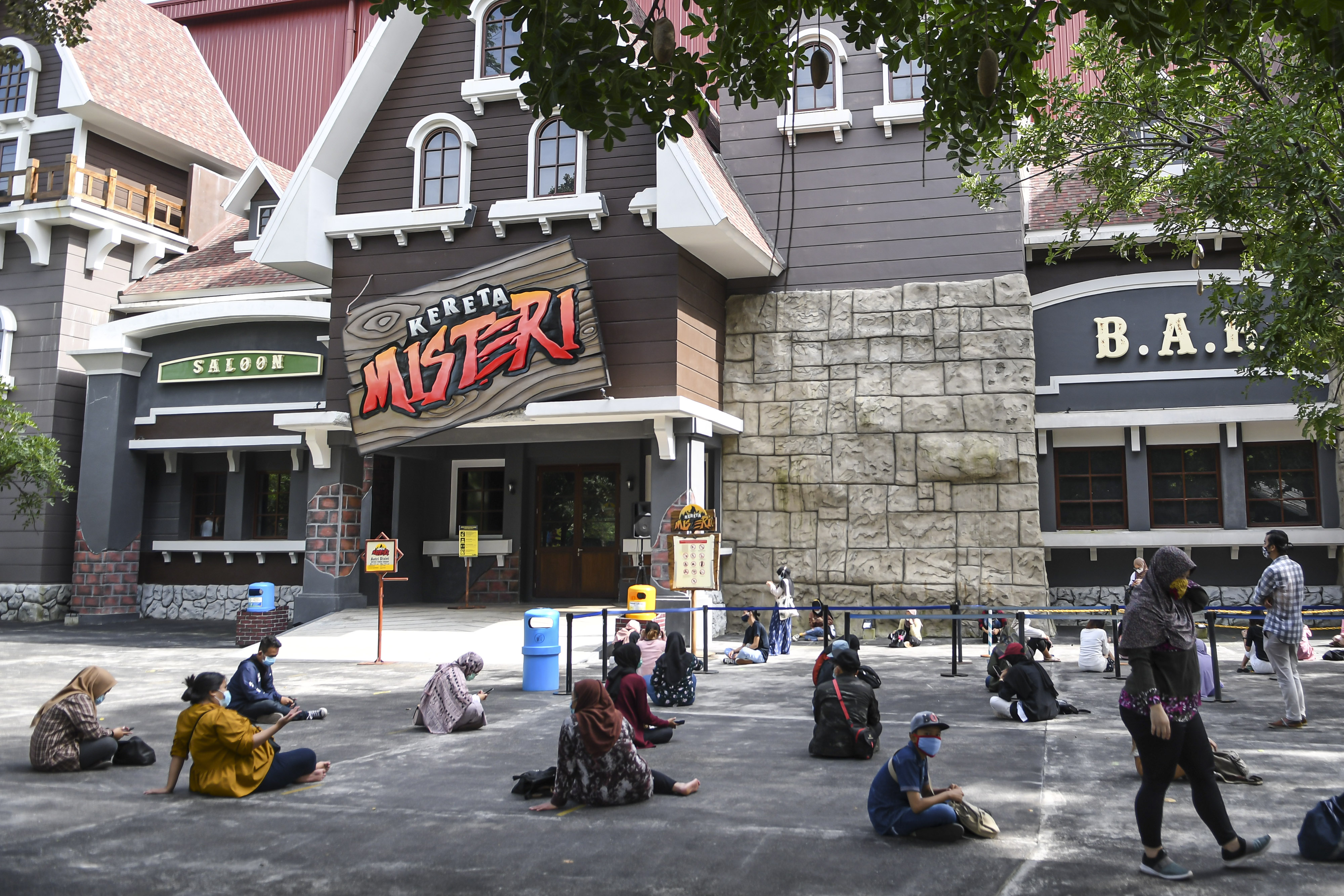 Sejumlah pengunjung duduk berjaga jarak saat antre untuk memasuki wahana di Dunia Fantasi, Ancol,