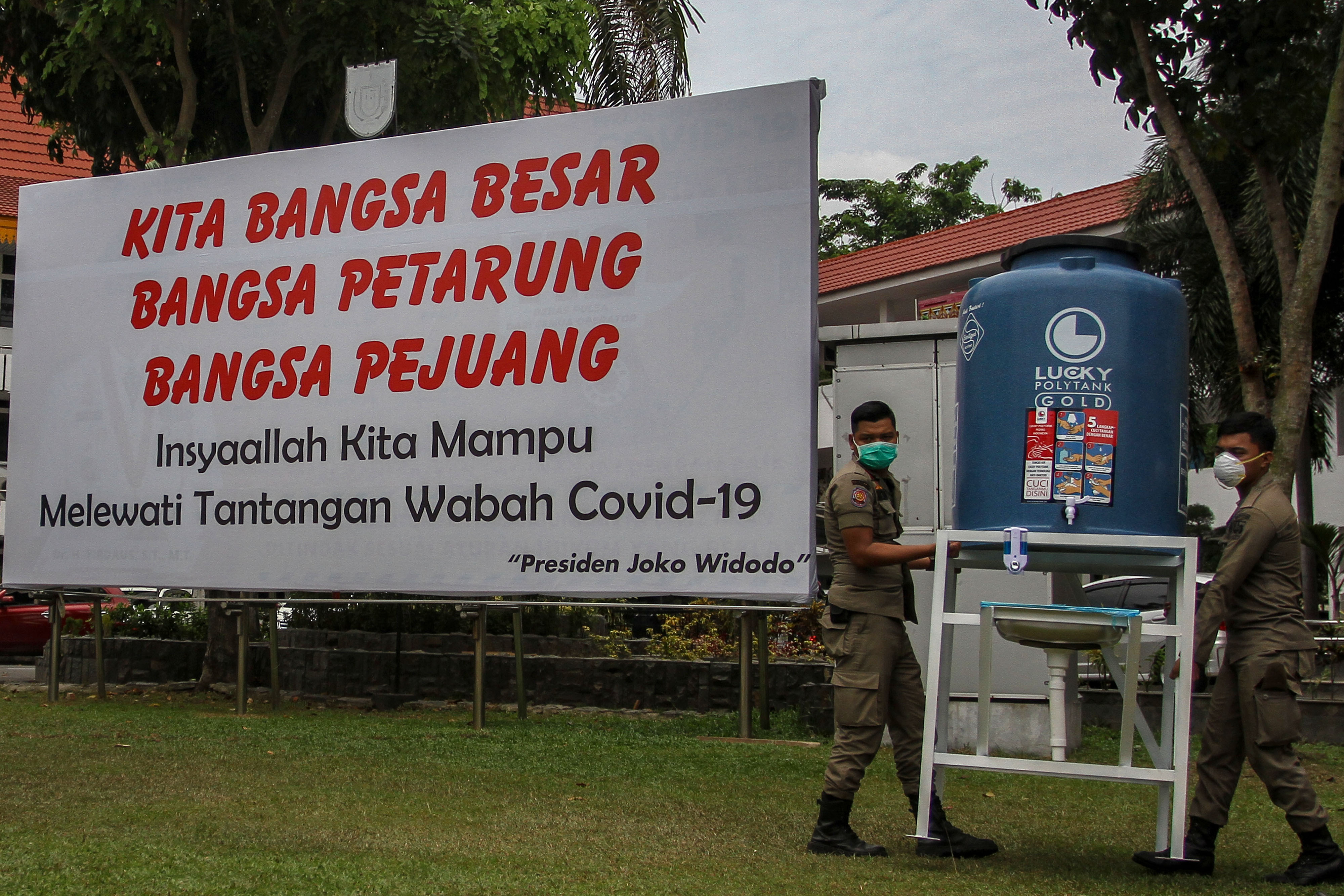 Petugas Satpol PP tengah memindahkan tempat cuci tangan untuk menerapkan protokol kesehatan.