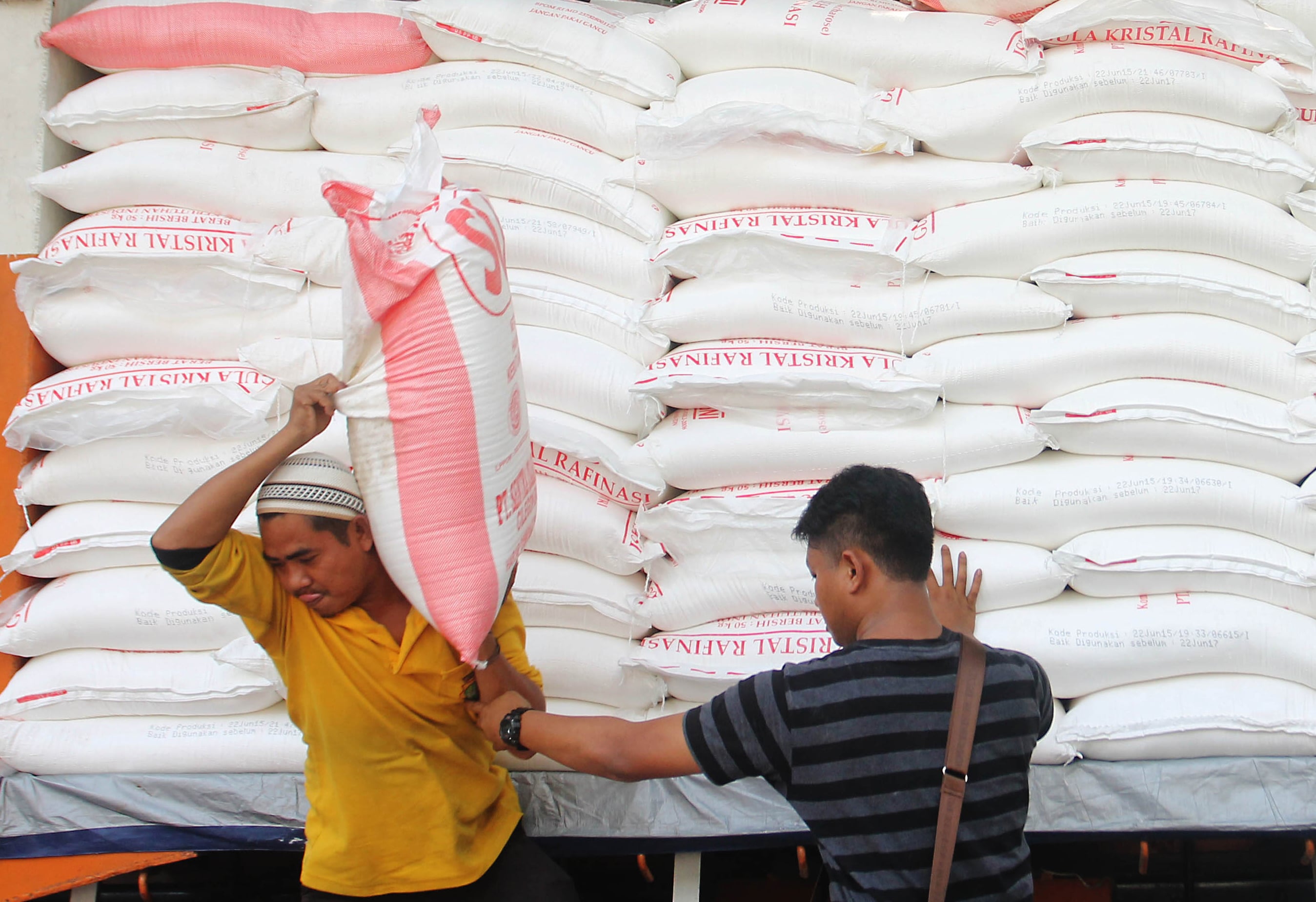 Kuli angkut turunkan gula dari truk pengangkut