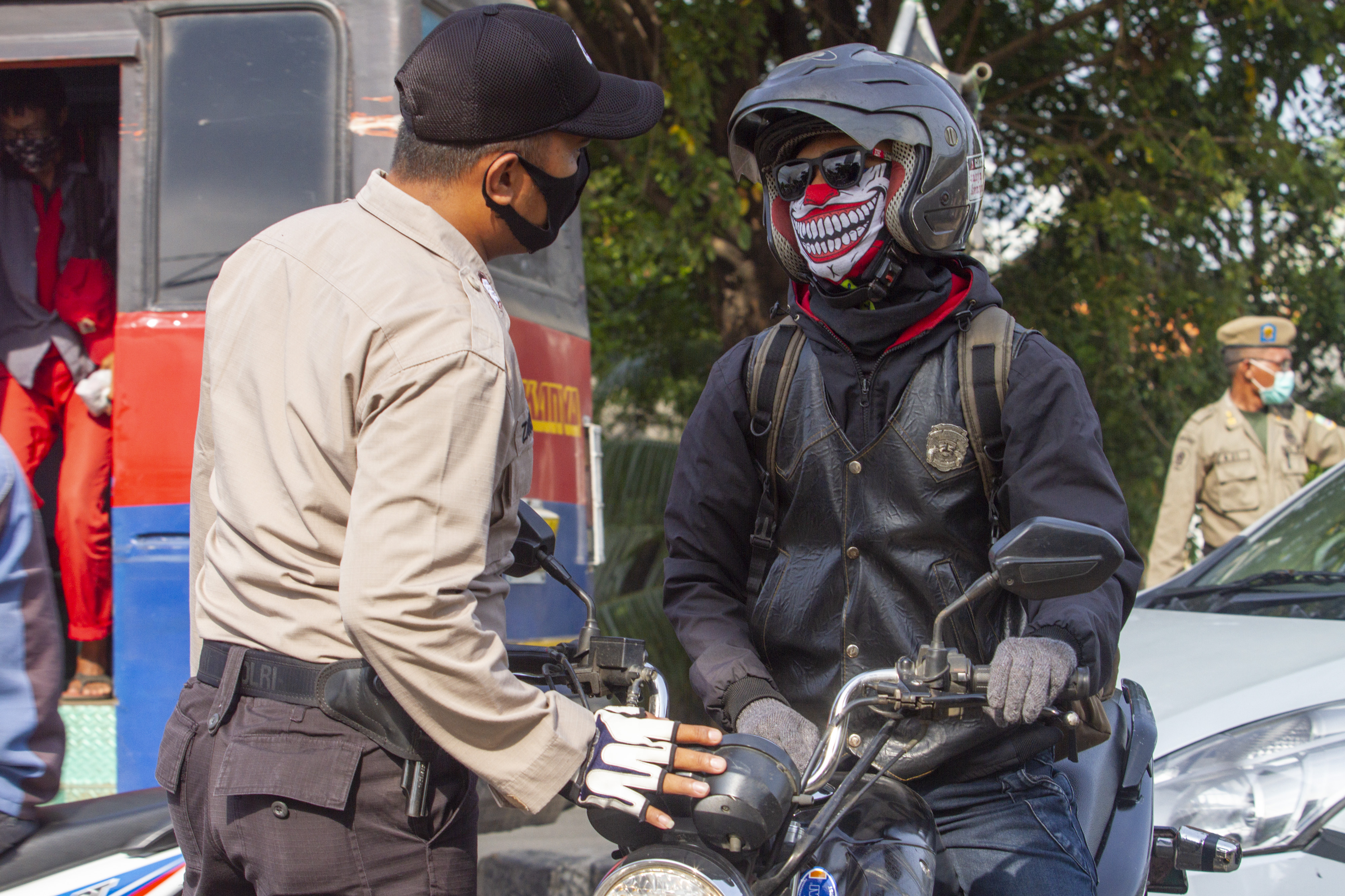 Petugas kepolisian memeriksa pengendara motor di pos penyekatan di perbatasan Bekasi-Karawang.