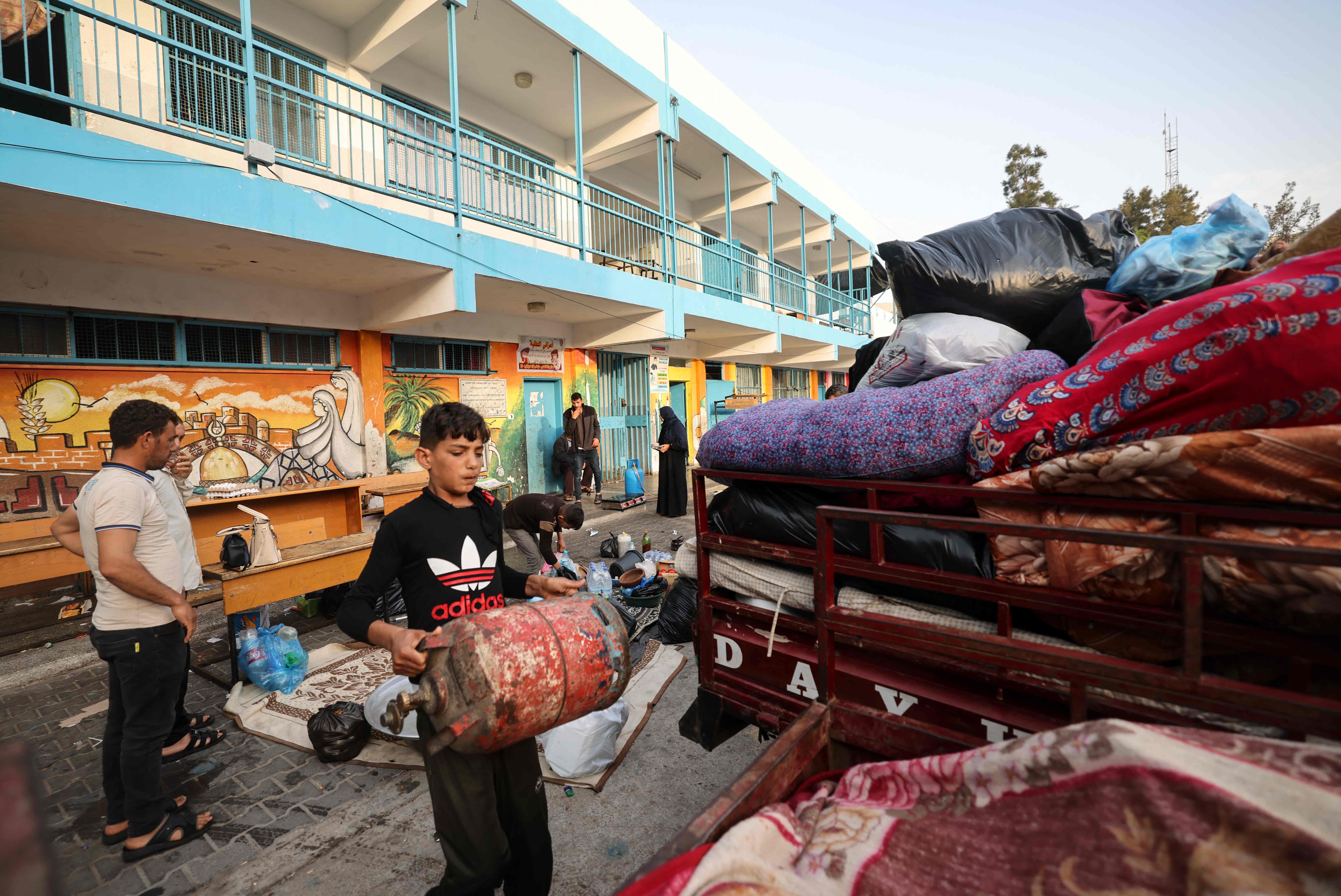 Warga Palestina yang sempat mengungsi di sekolah PBB di Gaza mengangkut barang mereka untuk kembali ke rumah pascagencatan senjata.