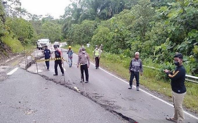 Personel Polres Murung Raya memasang garis polisi pada jalan yang retak di Km 61 Puruk Cahu-Muara Teweh, Rabu (19/5).