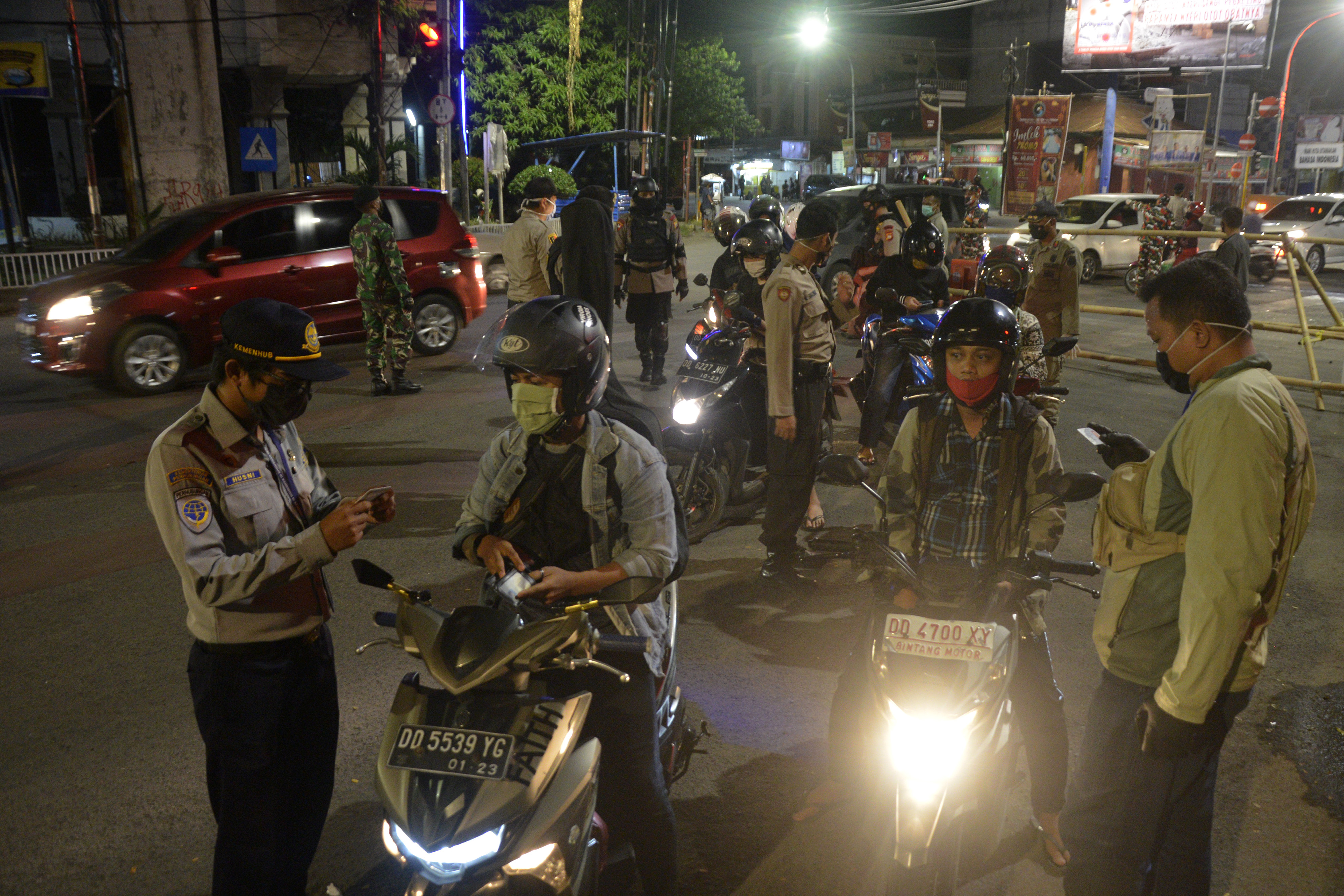 Petugas gabungan memeriksa sejumlah pengendara yang akan melewati pemeriksaan di perbatasan Kabupaten Gowa dan Makassar, Sulawesi Selatan.