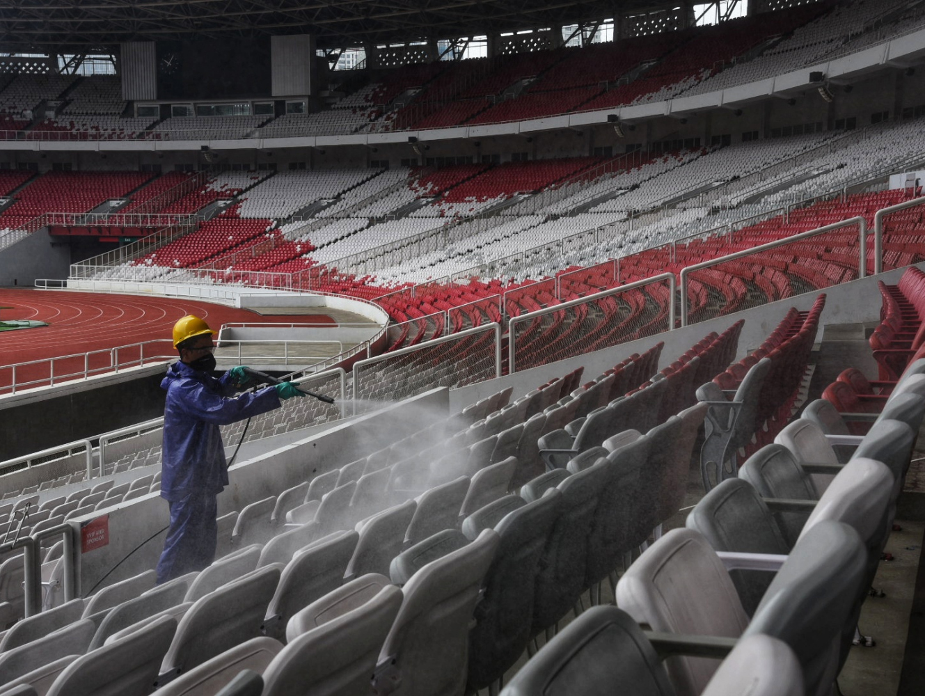 Ilustrasi petugas saat menyemprotkan cairan disinfektan ke bangku stadion.