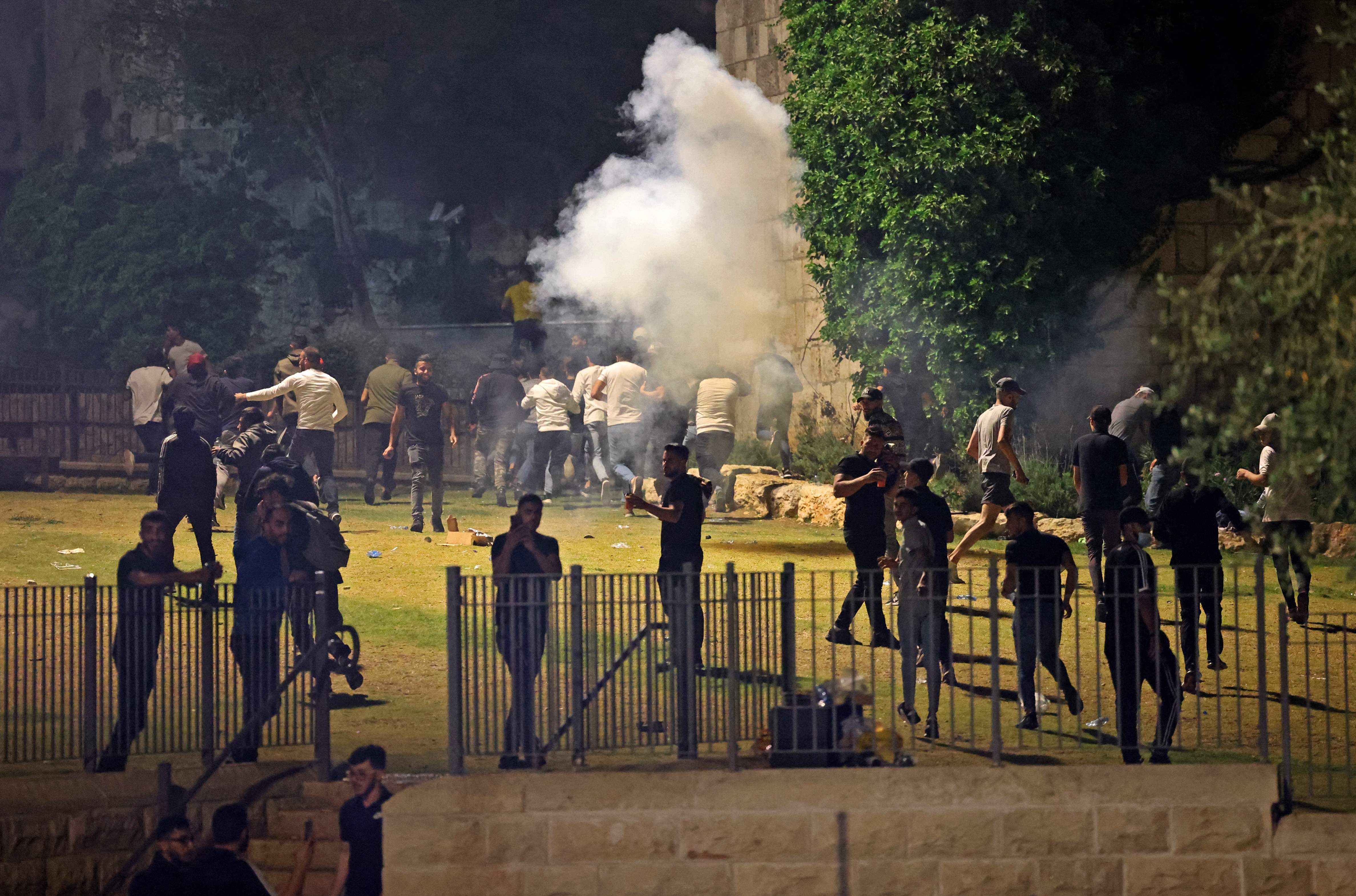 Warga Palestina melarikan diri saat polisi Israel menembakkan gas air mata dalam bentrokan di Jerusalem.