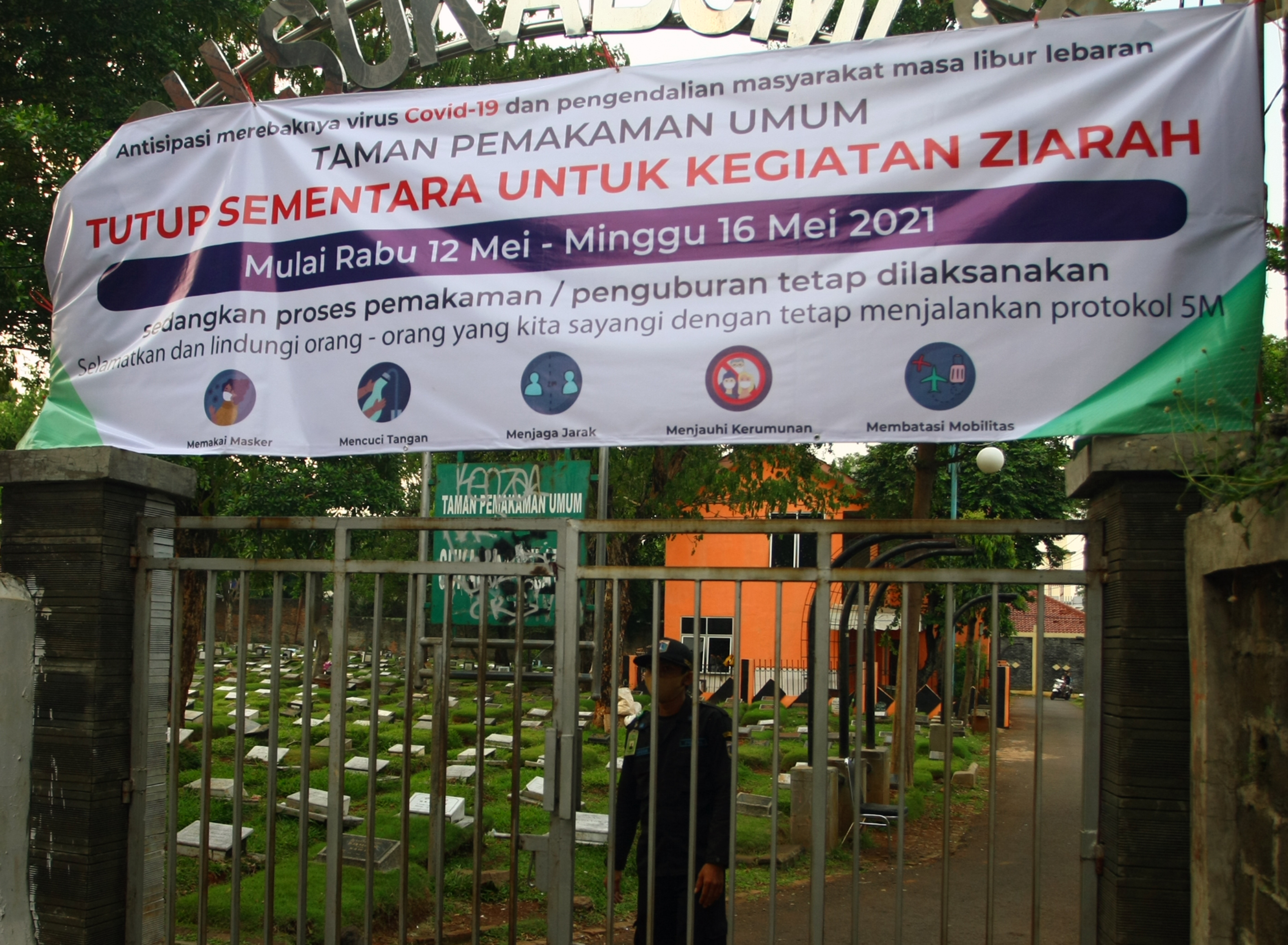 Petugas berjaga di gerbang masuk Tempat Pemakaman Umum (TPU) Sukabumi Selatan yang ditutup di Jakarta Barat
