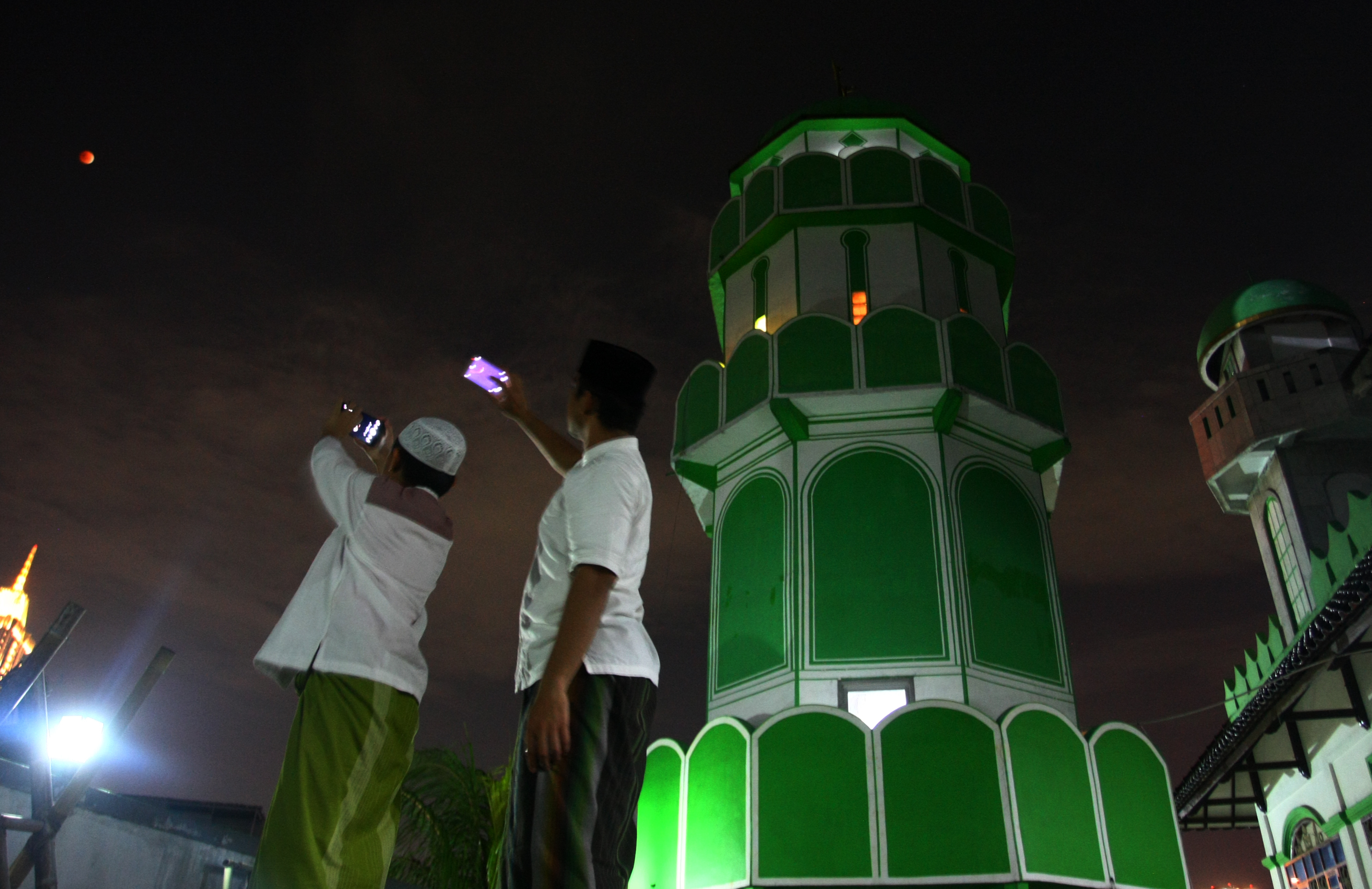 FENOMENA GERHANA BULAN: Dua jemaah tengah mengabadikan fenomena gerhana bulan seusai melaksanakan salat sunah gerhana bulan, 3 tahun lalu.