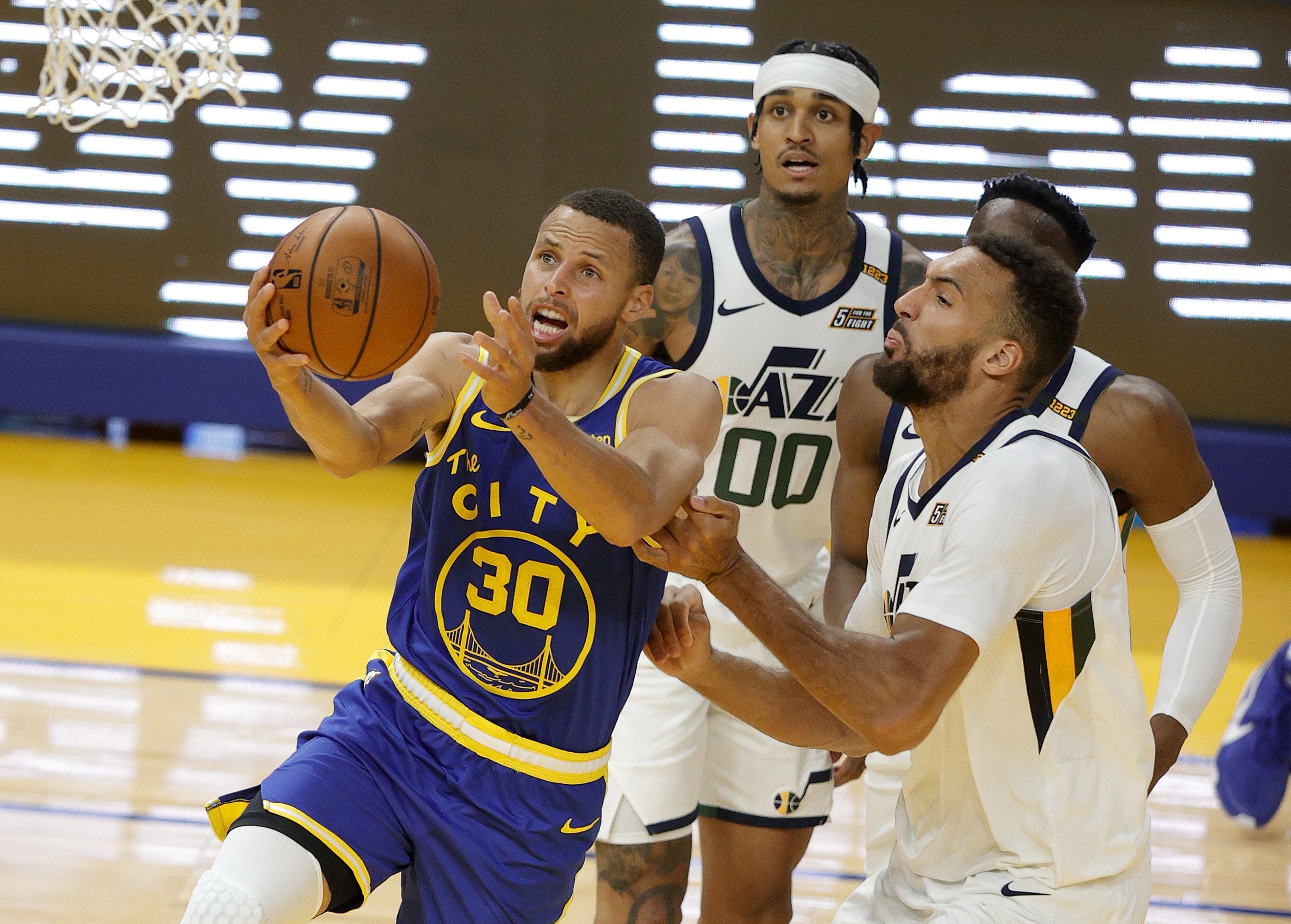 Pemain guard Golden State Warriors, Stephen Curry (kiri), dihalangi Rudy Gobert dari Utah Jazz pada laga lanjutan Liga NBA.