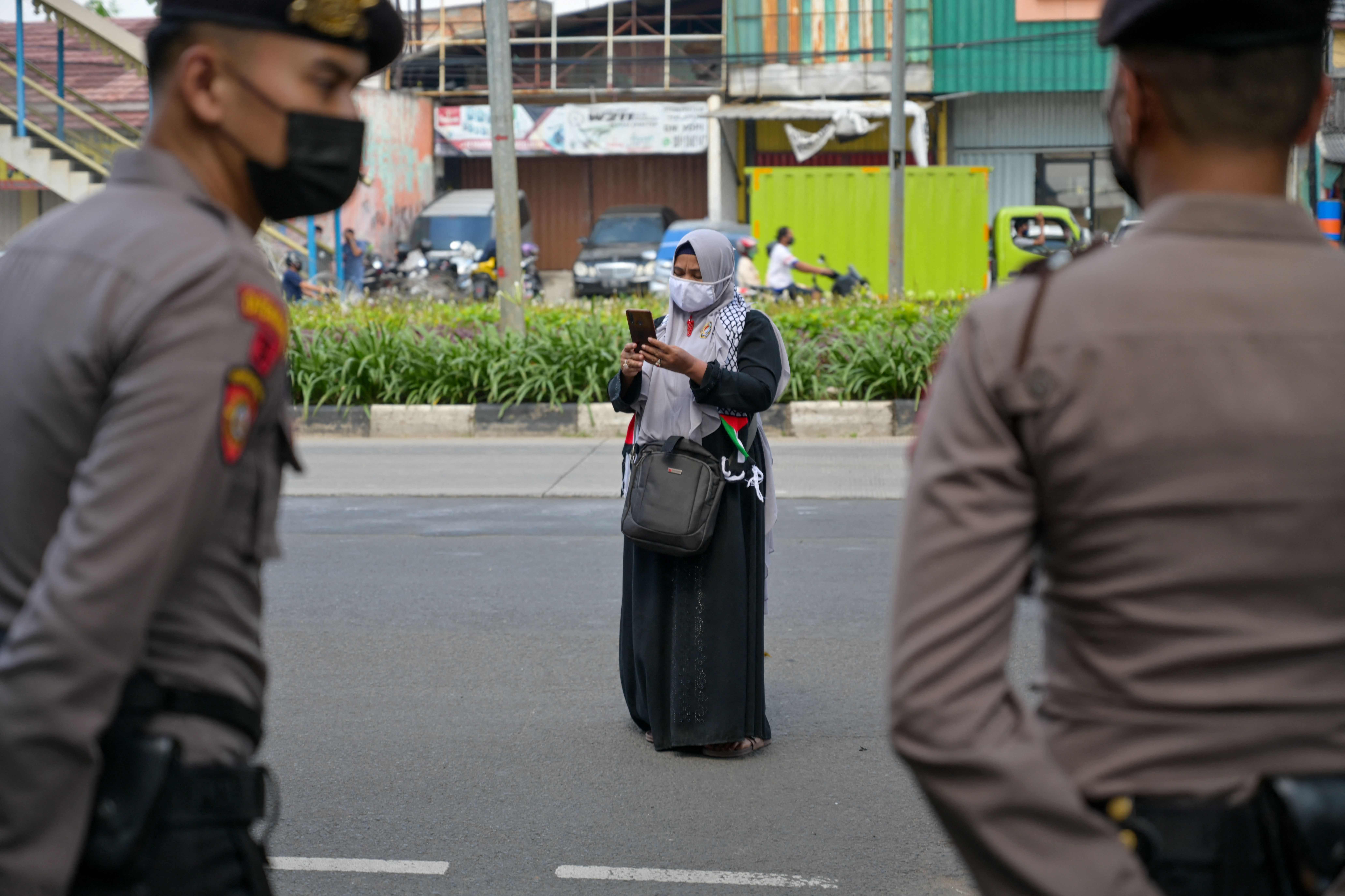 Polisi berjaga saat pengunjuk rasa mengambil foto dengan ponsel ketika sidang vonis Rizieq Shihab, Jakarta, Kamis (27/5).
