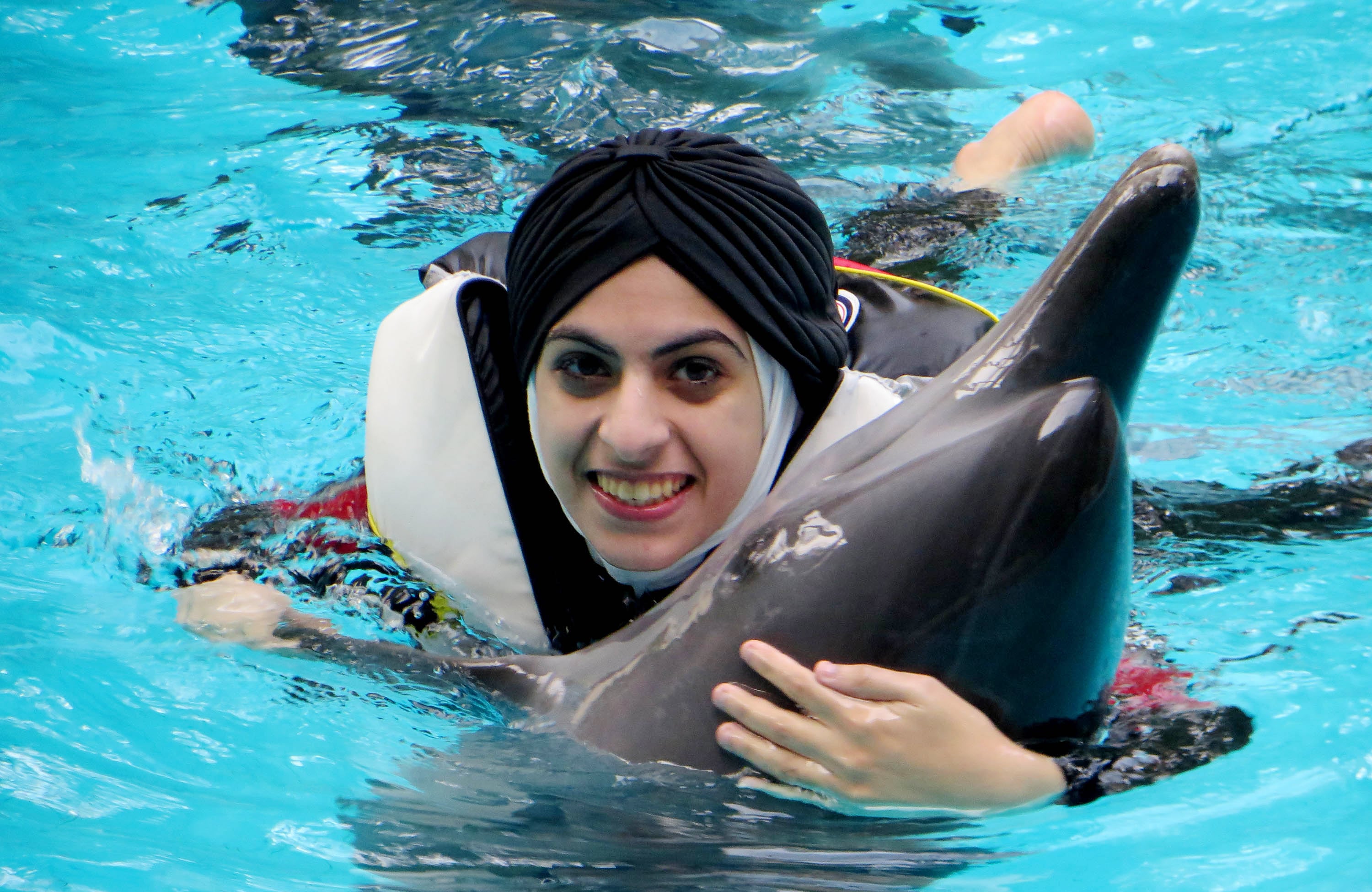 Turis Iran memeluk lumba-lumba dari jenis bottlenose dolphin, di Taman safari Indonesia (TSI), Cisarua, Bogor, Jawa Barat. 