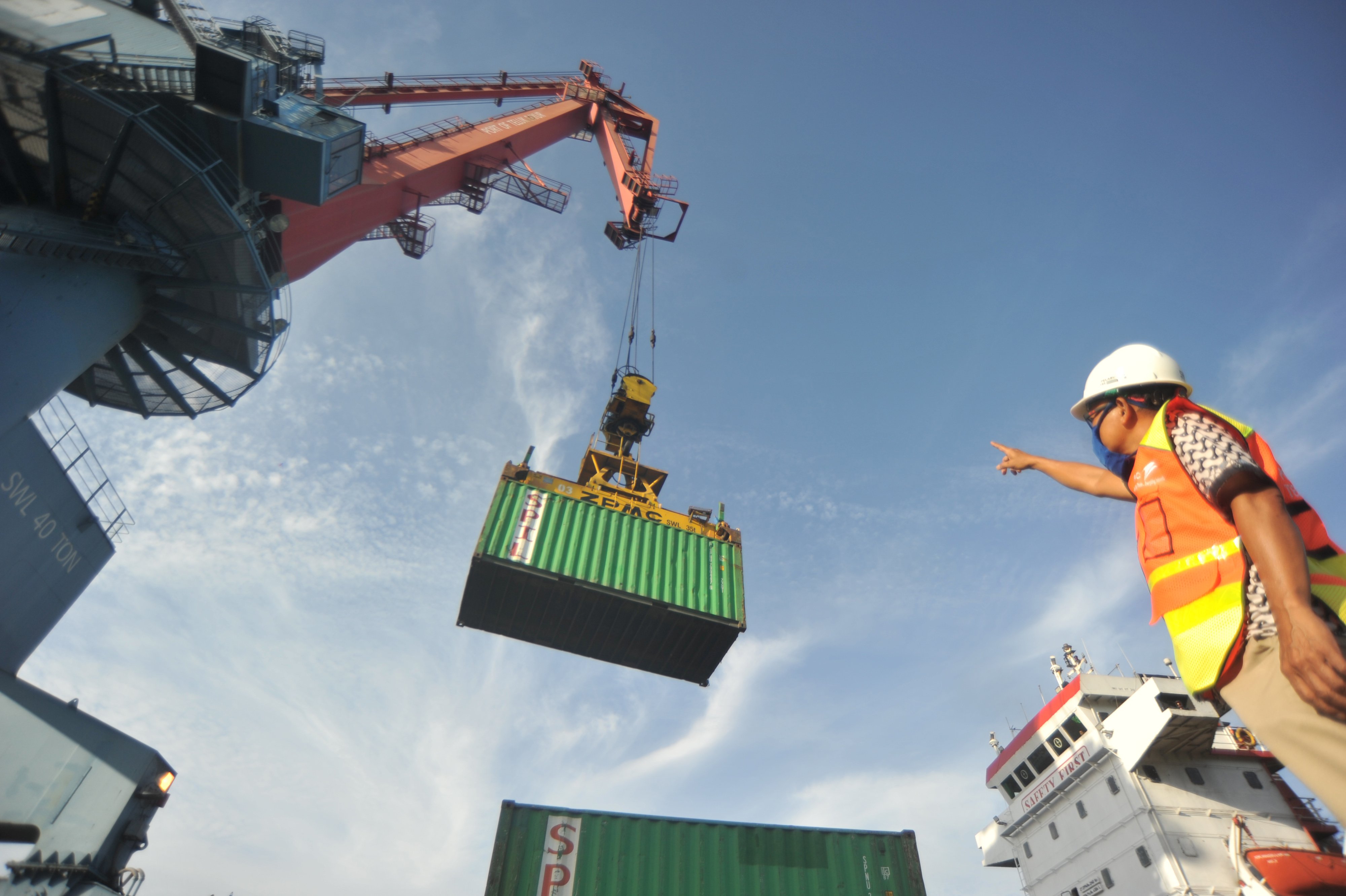 Petugas Pelindo II menggunakan masker memantau aktivitas bongkar muat peti kemas di Pelabuhan Teluk Bayur, Padang, Sumatera Barat, Jumat