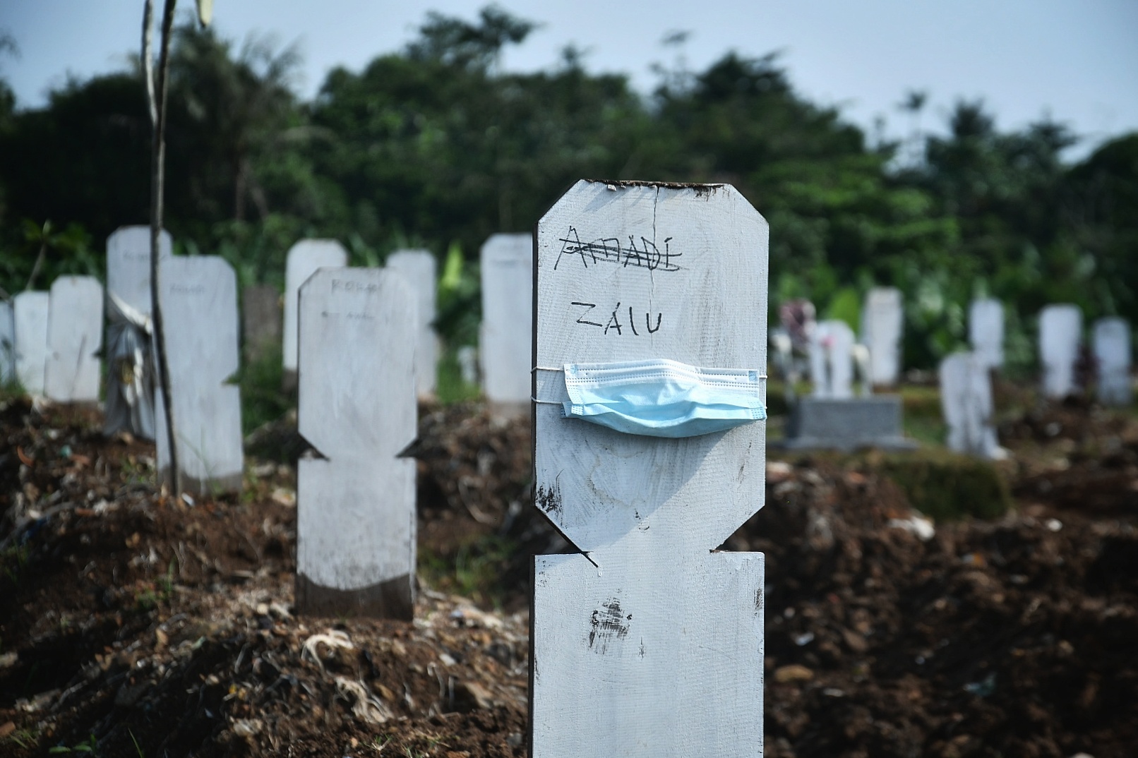 Sebuah masker dipasang di sebuah nisan di makam TPU khusus covid-19 Srengseng Sawah, Jakarta.