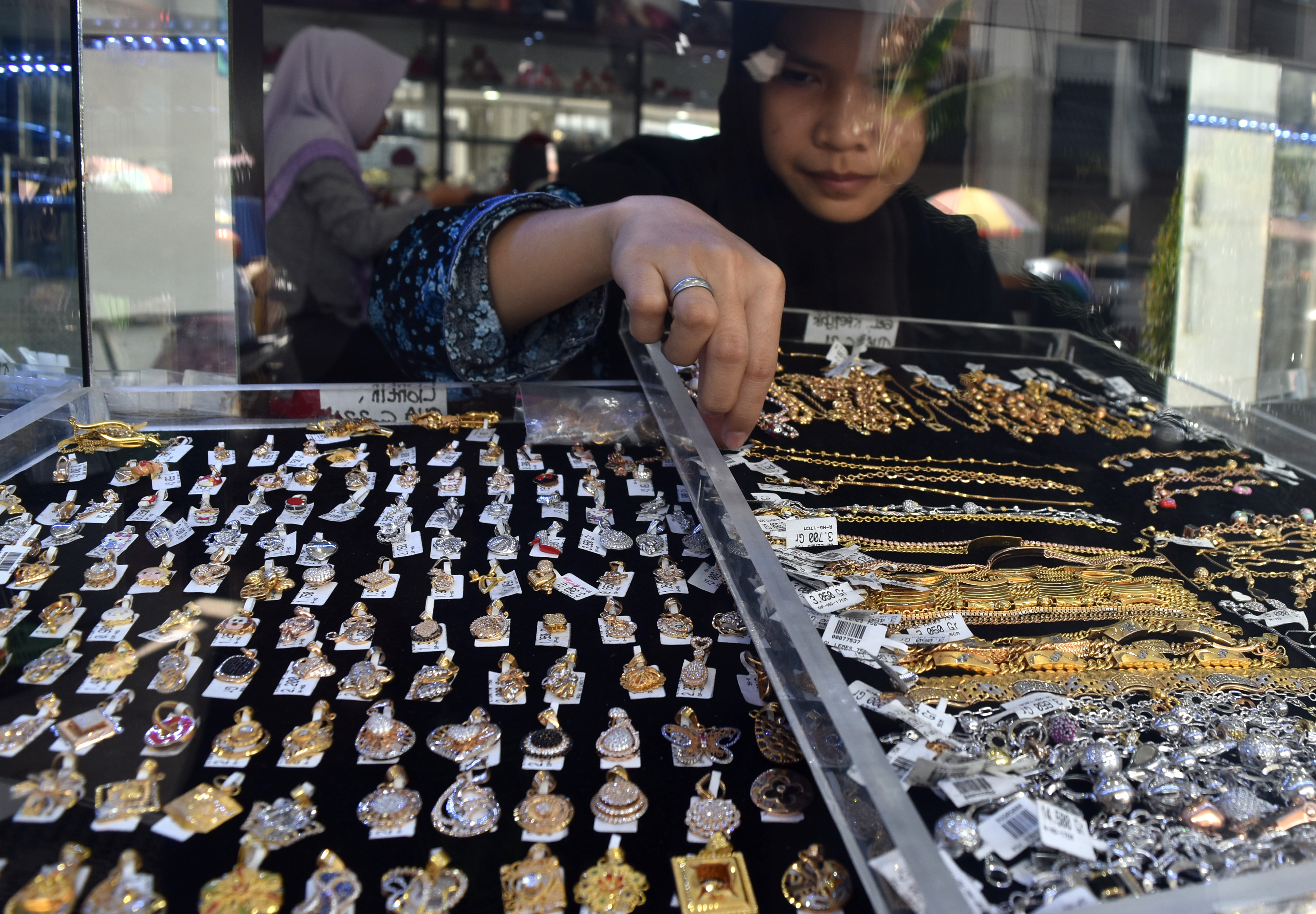 Ilustrasi karyawan menata perhiasan emas di sebuah toko.