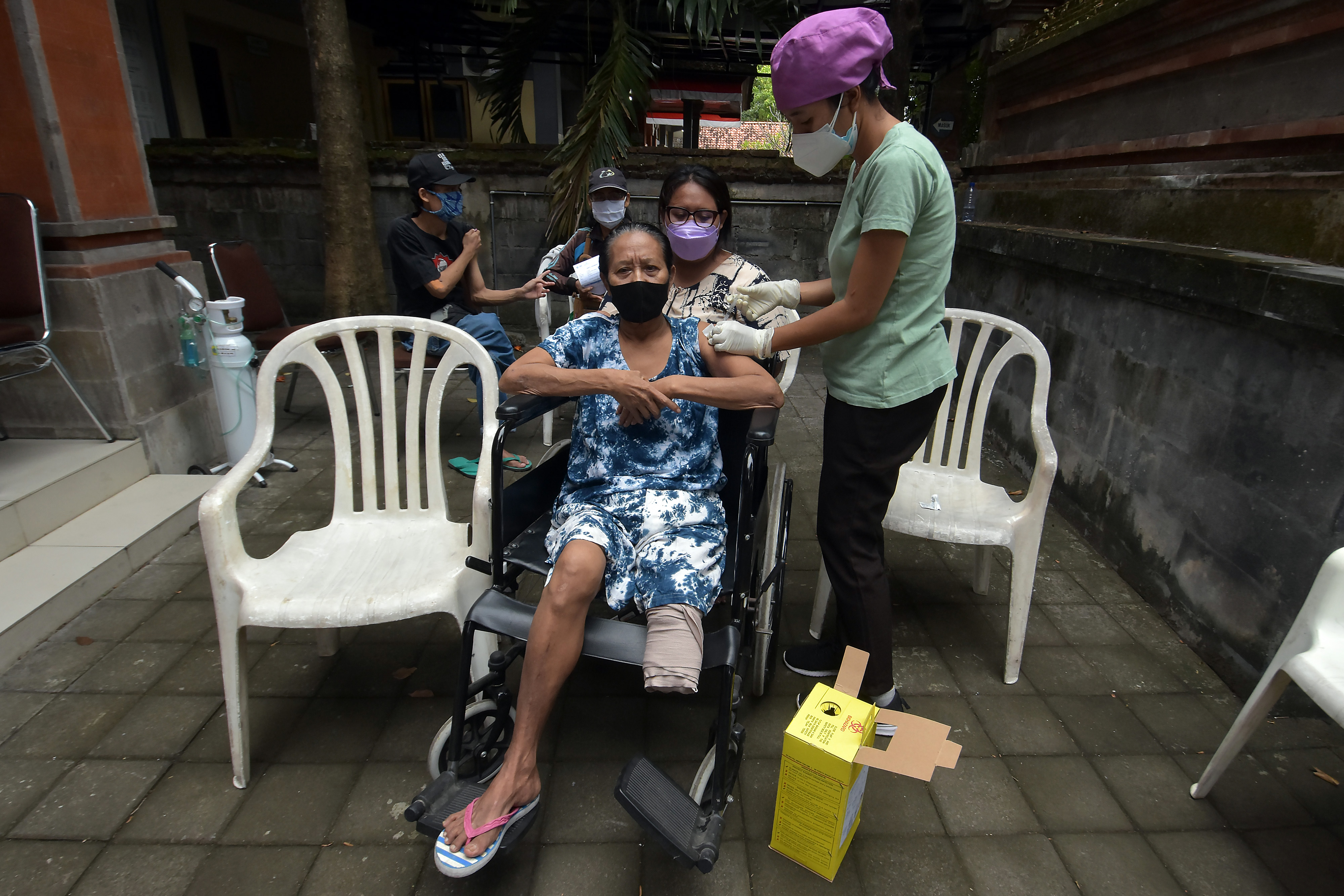  Petugas kesehatan menyuntikkan vaksin Covid-19 kepada penyandang tuna daksa di Rumah Bisabillitas, Denpasar, Bali.
