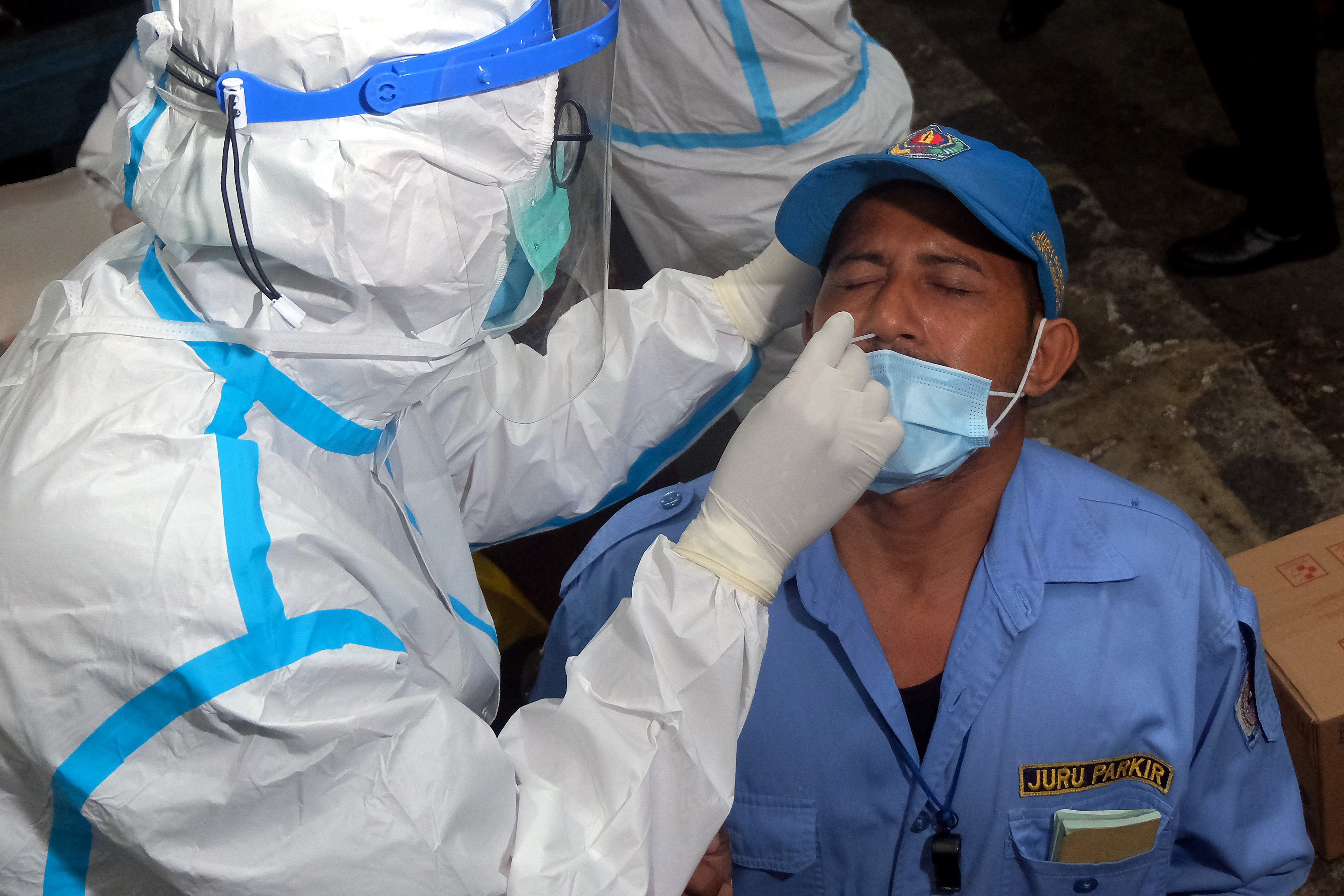 Petugas mengambil sampel tes cepat Antigen dari seorang juru parkir saat pelacakan covid-19 di Pasar Kreneng, Denpasar, Bali.