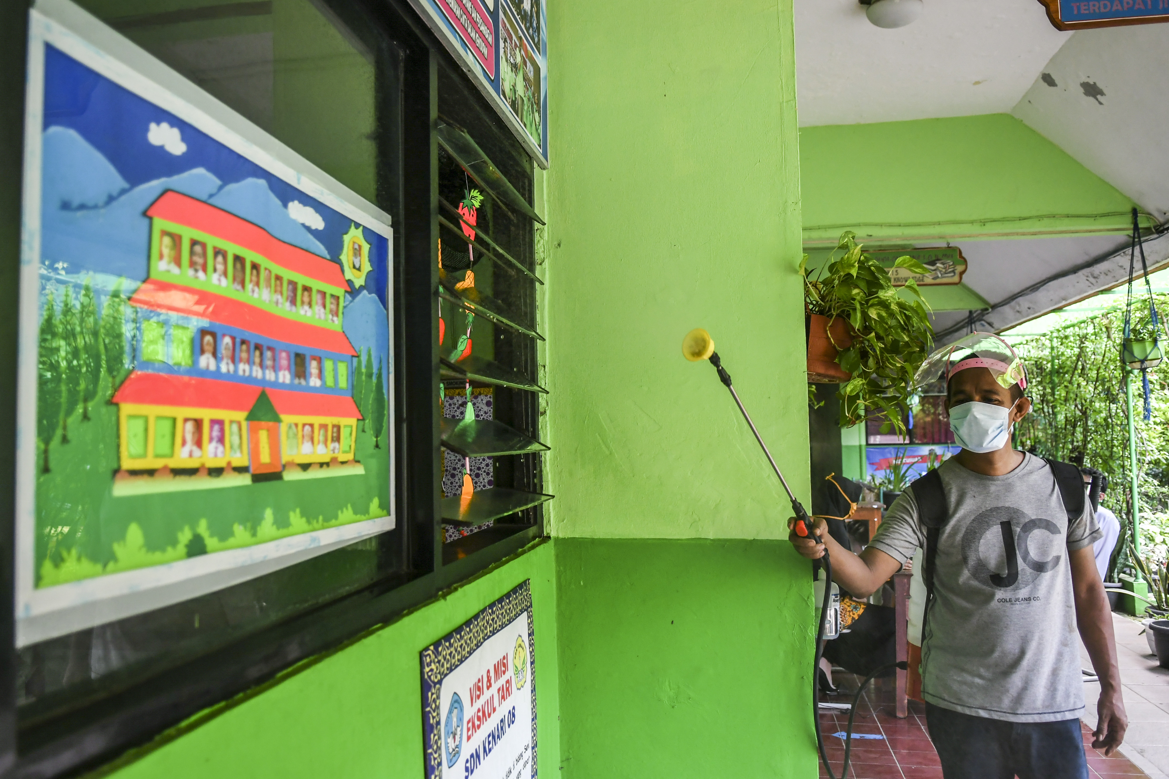 Petugas menyemprotkan disinfektan di ruang kelas SD Kenari 08 Pagi, Jakarta, Jumat (18/6/2021).