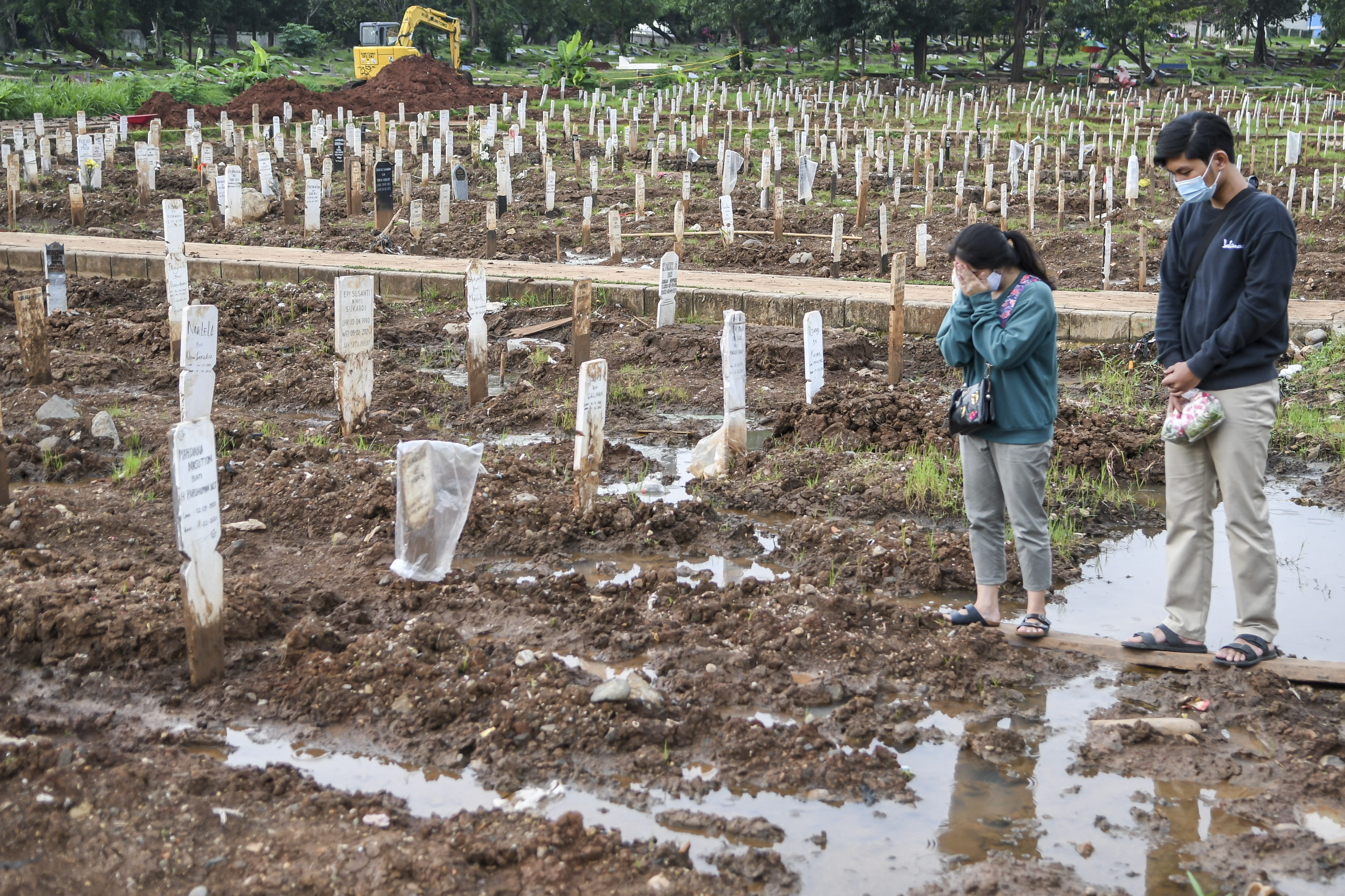 Peziarah berdoa di areal pemakaman khusus protokol covid-19 di TPU Bambu Apus, Jakarta.