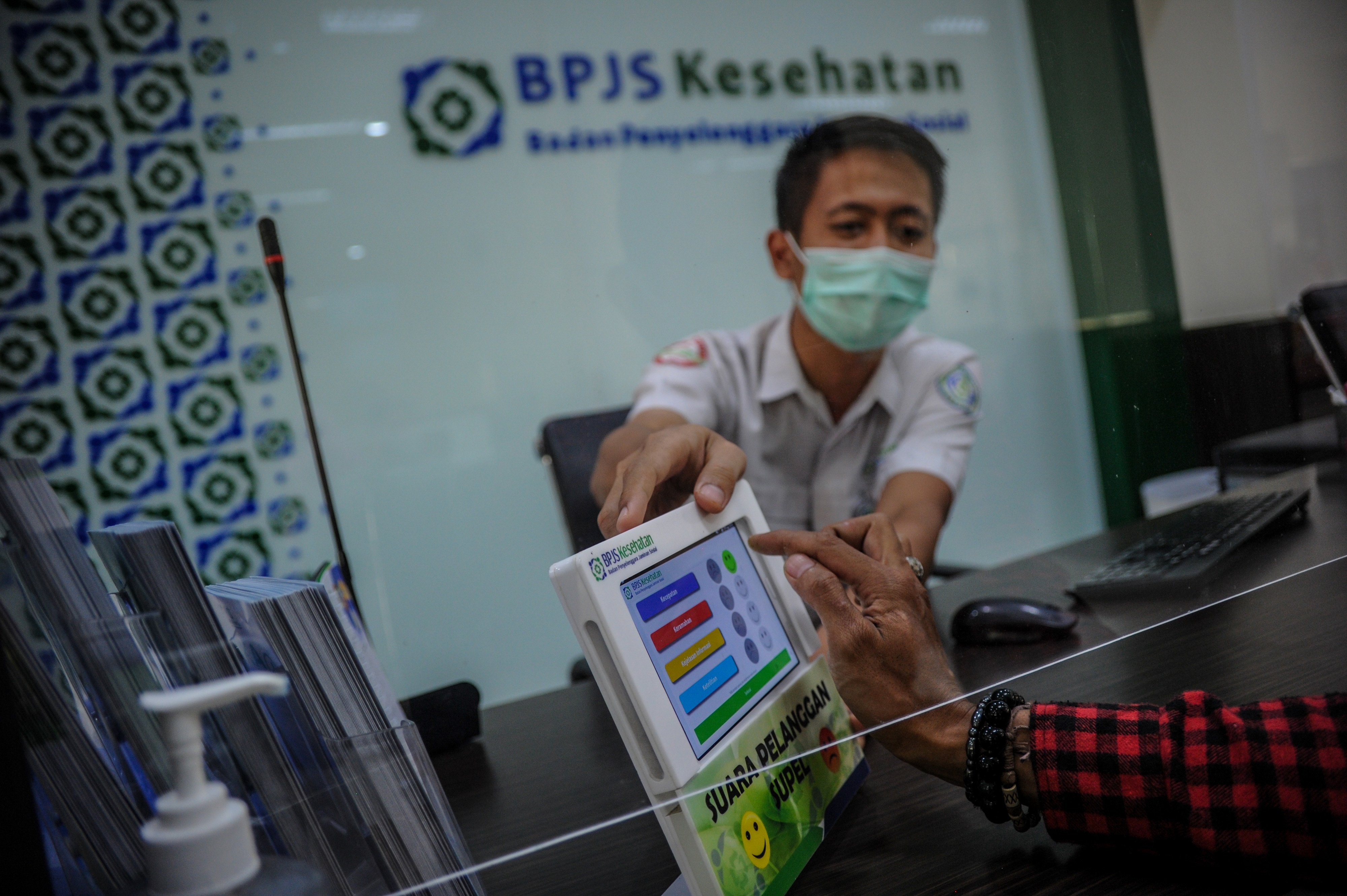 Ilustrasi pegawai BPJS Kesehatan saat melayani warga di tengah pandemi covid-19.