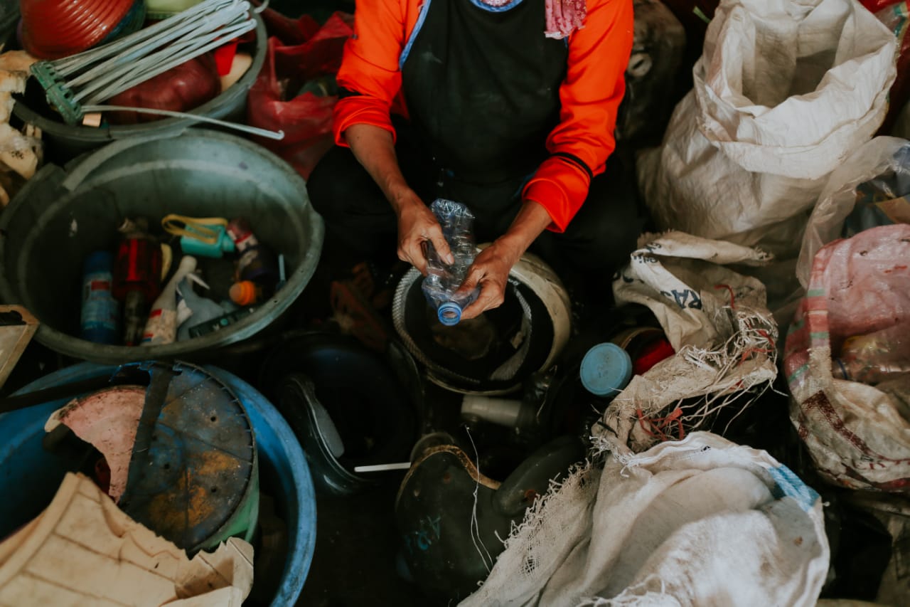 Seorang pemulung tengah memilha sampah plastik.