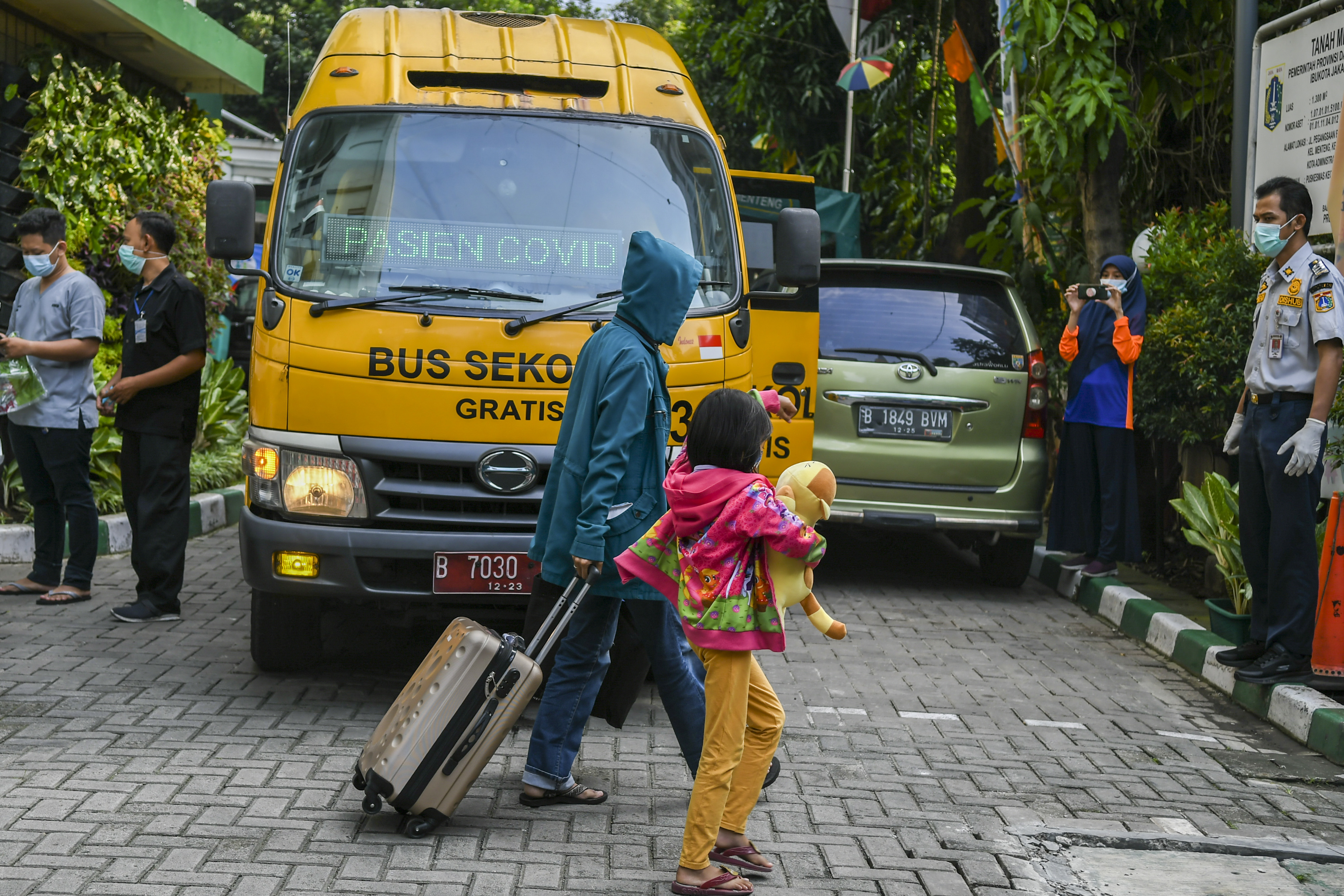 Pasien covid-19 memasuki bus sekolah untuk dibawa ke RSDC Wisma Atlet Kemayoran, Jakarta.