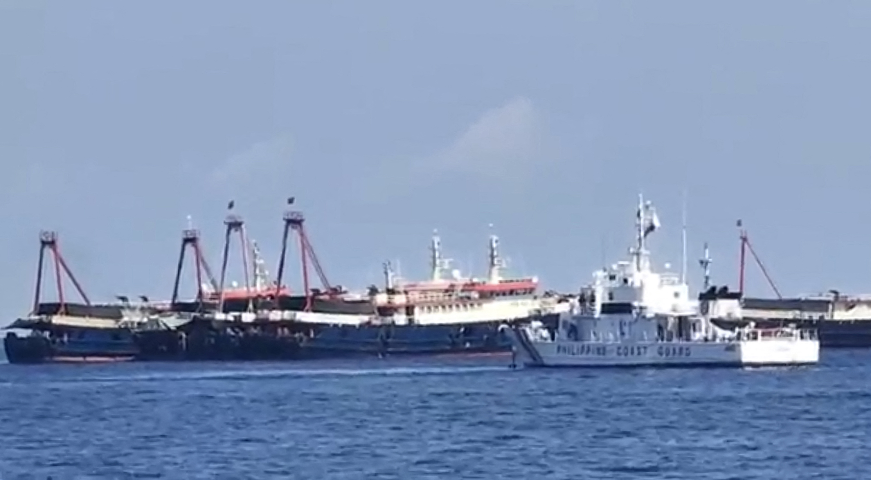 Kapal penjag pantai Filipina BRP Cabra (depan) mengawasi kapal-kapal Tiongkok di Kepulauan Sabina, Laut China Selatan.