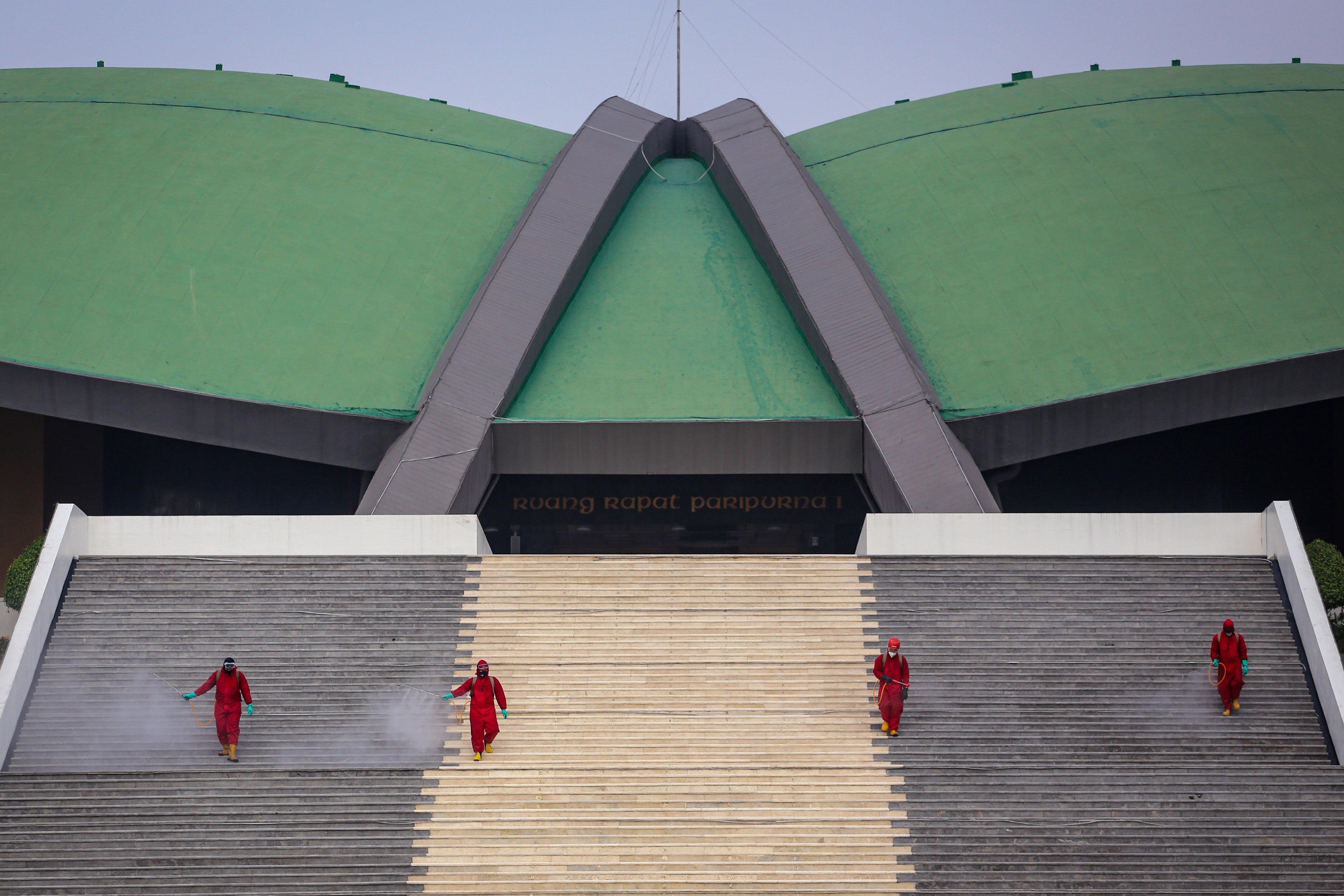 Petugas pemadam kebakaran menyemprotkan cairan disinfektan di area Gedung DPR/MPR RI