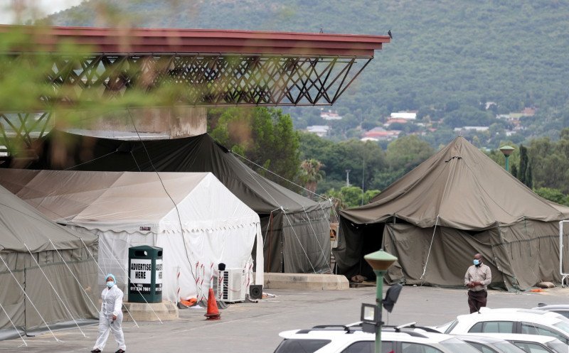 Petugas kesehatan berjalan melewati sejumlah tenda yang dipasang di lapangan parkir Rumah Sakit Akademi Steve Biko di Pretoria, Afrika Selat