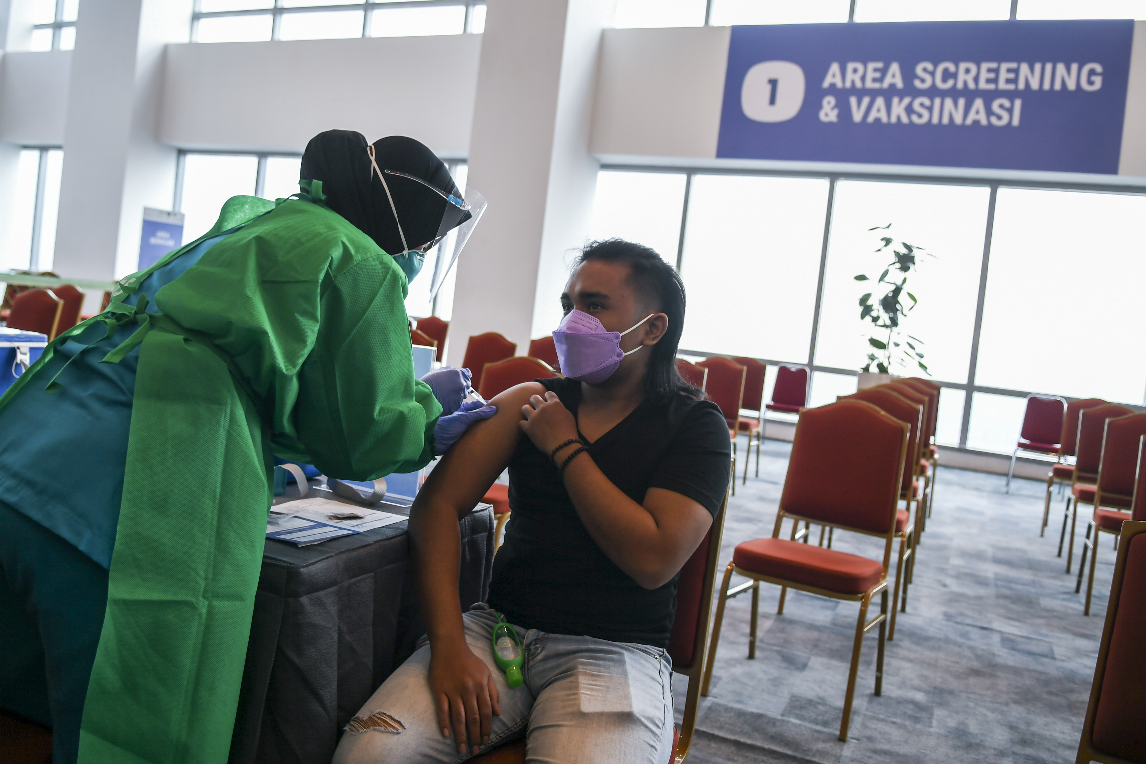 Vaksinator menyuntikan vaksin COVID-19 Astra Zeneca dosis pertama kepada seorang pelaku ekonomi kreatif