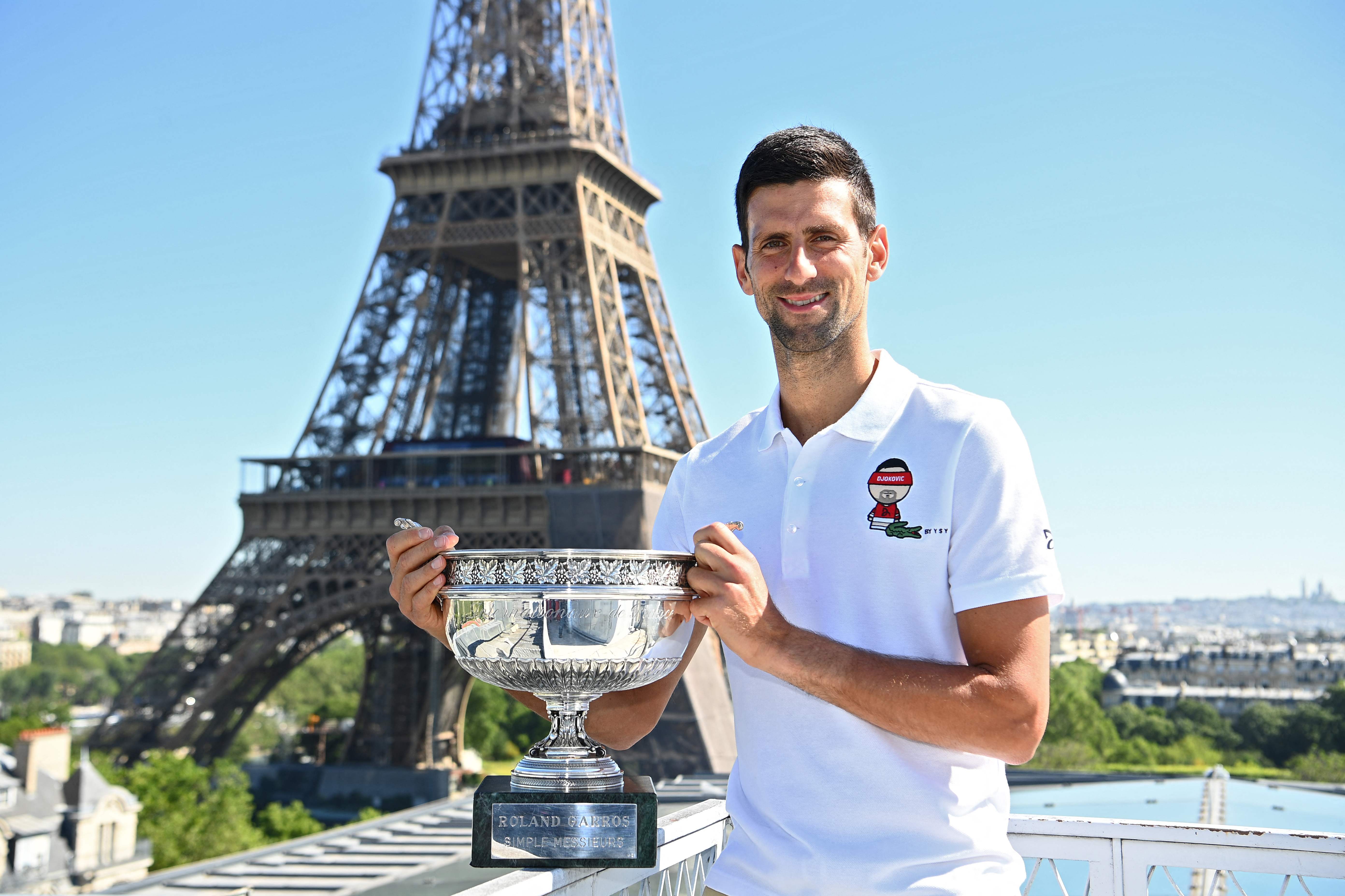 Petenis Serbia Novak Djokovic berpose dengan trofi Prancis Terbuka dengan latar belakang Menara Eiffel di Paris.