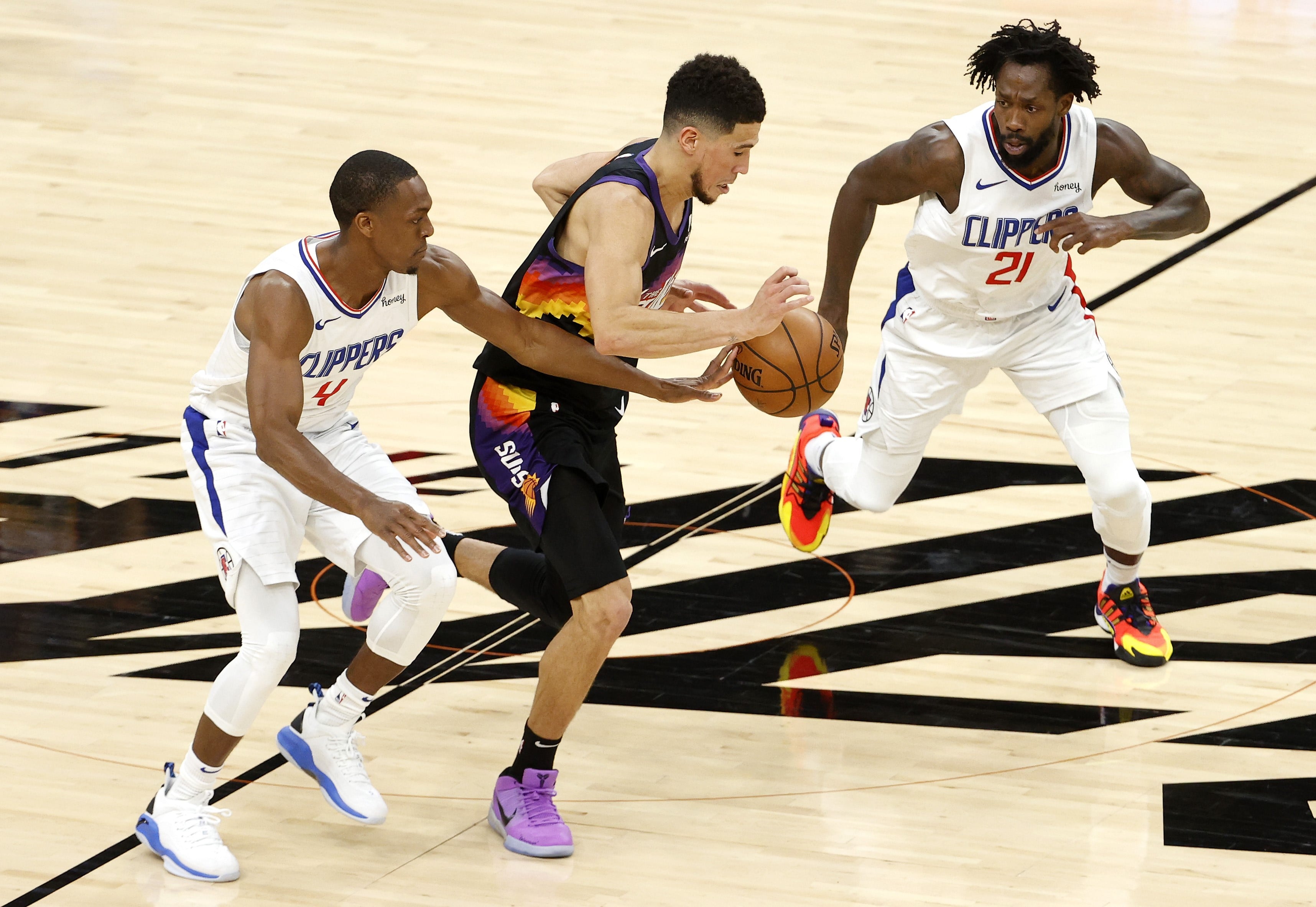 Pemain Phoenix Suns Devin Booker (tengah) berusaha melewati hadangan dua pemain Los Angeles Clippers di Gim 1 Final Wilayah Barat NBA.