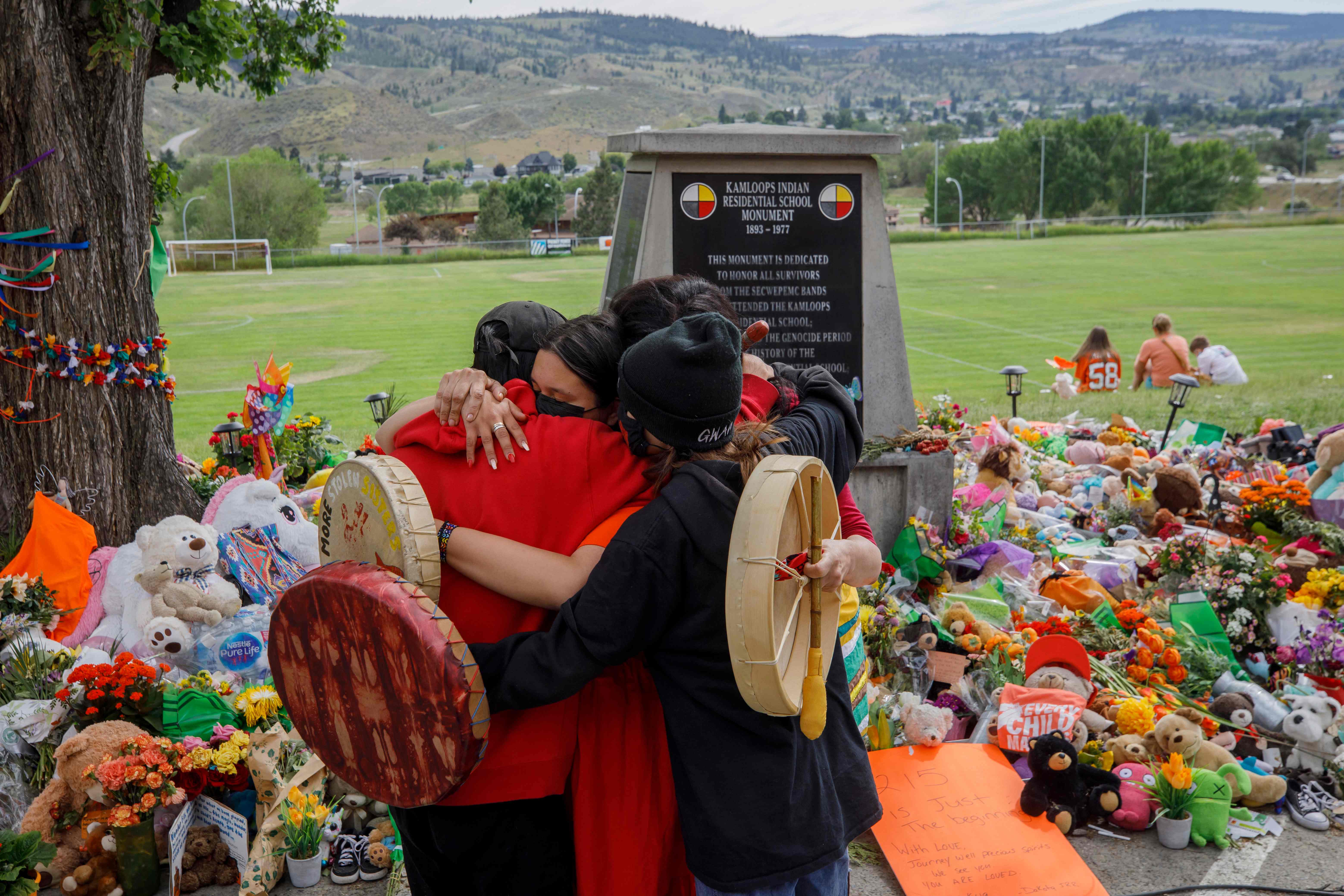 Warga Mosakahiken Cree Nation berpelukan di depan tugu peringatan darurat di bekas Sekolah Perumahan Indian Kamloops, Kanada