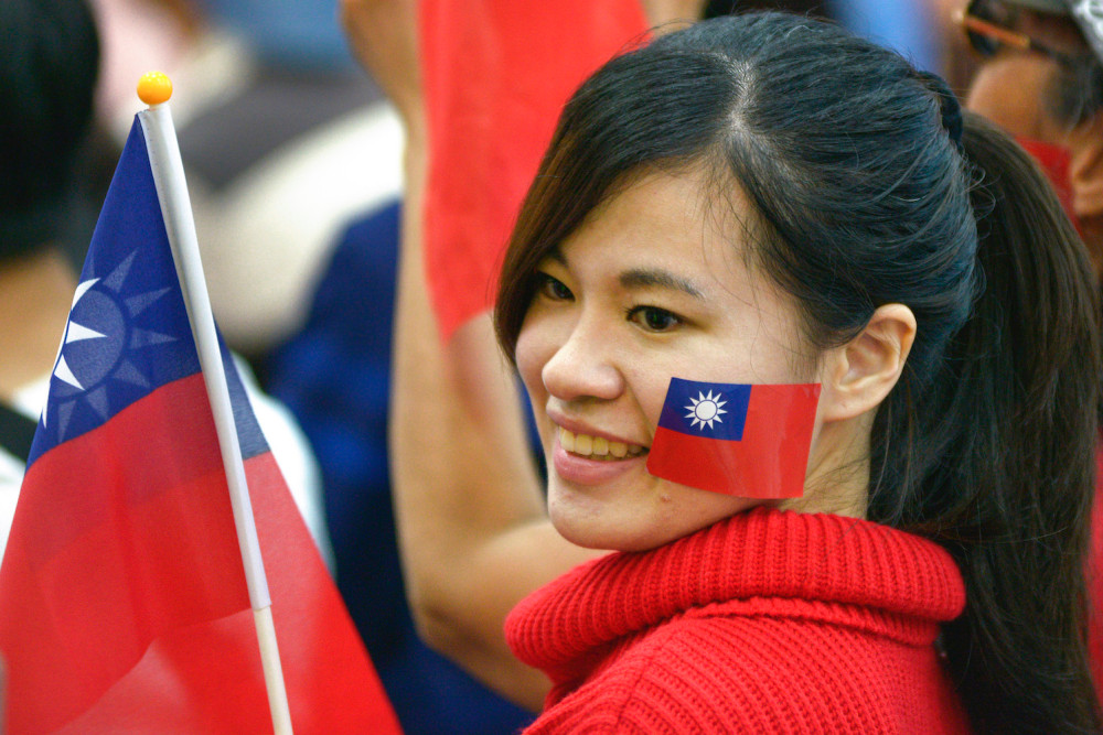 Seorang wanita, warga negara Taiwan, mengibarkan bendera nasional saat pemillihan presiden di Taiwan.  