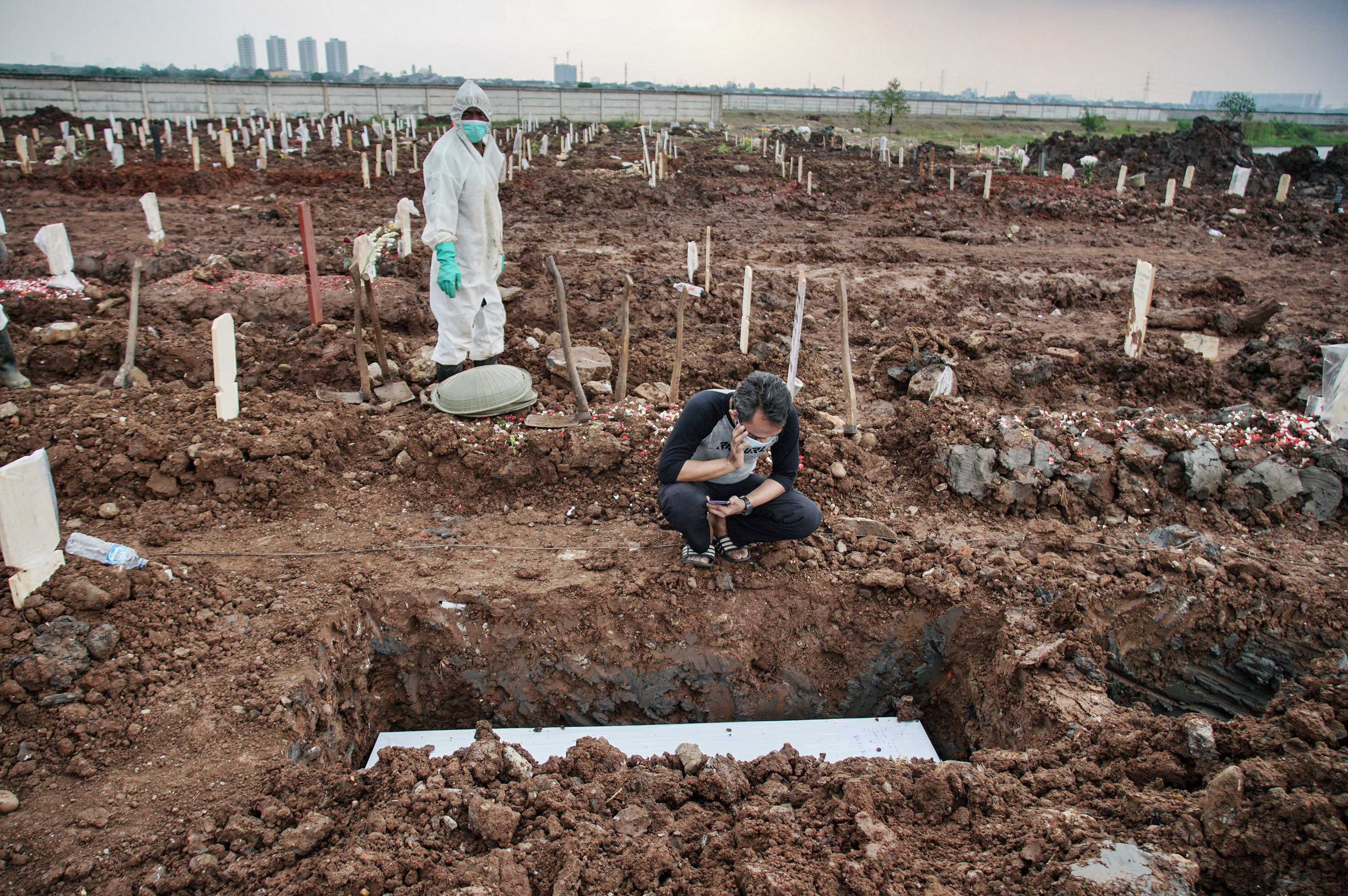 Warga mengumandangkan azan di dekat pusara keluarganya yang meninggal akibat covid-19 di TPU khusus covid-19 di Rorotan, Jakarta