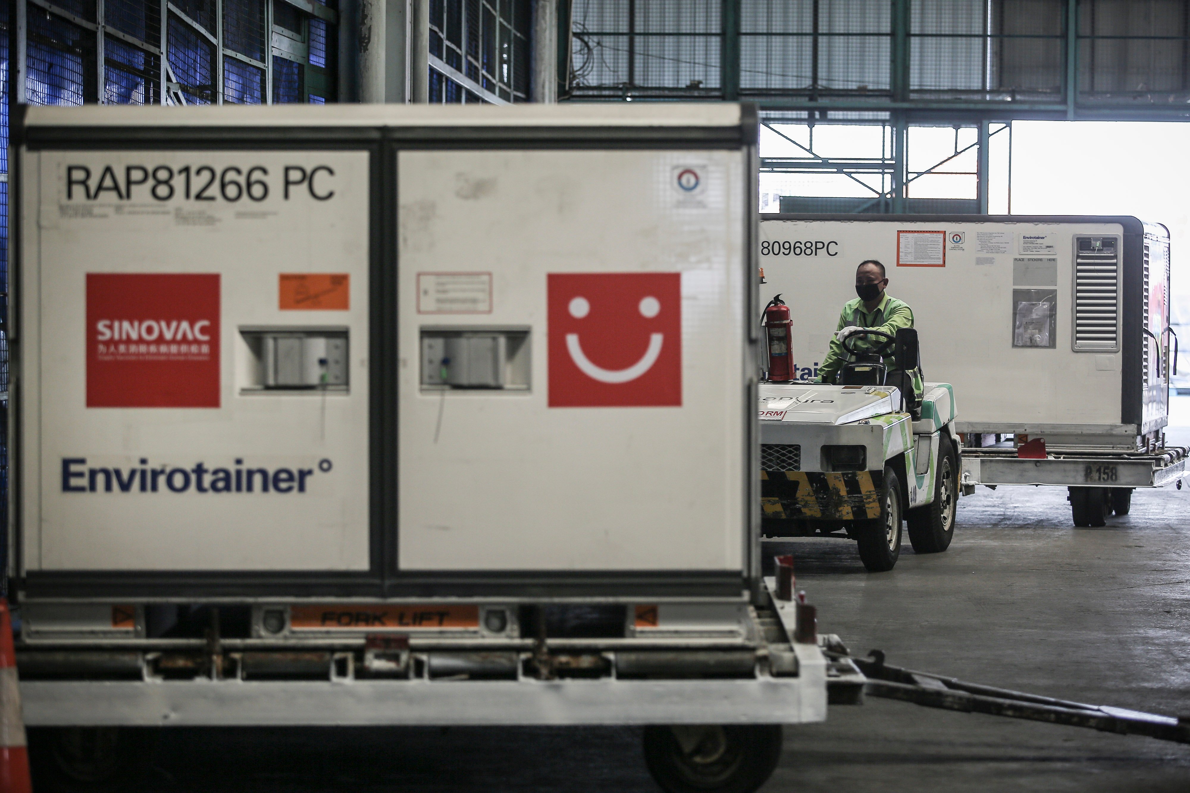 Petugas membawa Envirotainer berisi vaksin covid-19 setibanya di Teminal Cargo Bandara Soekarno Hatta, Tangerang, Banten, Senin (31/5/2021)