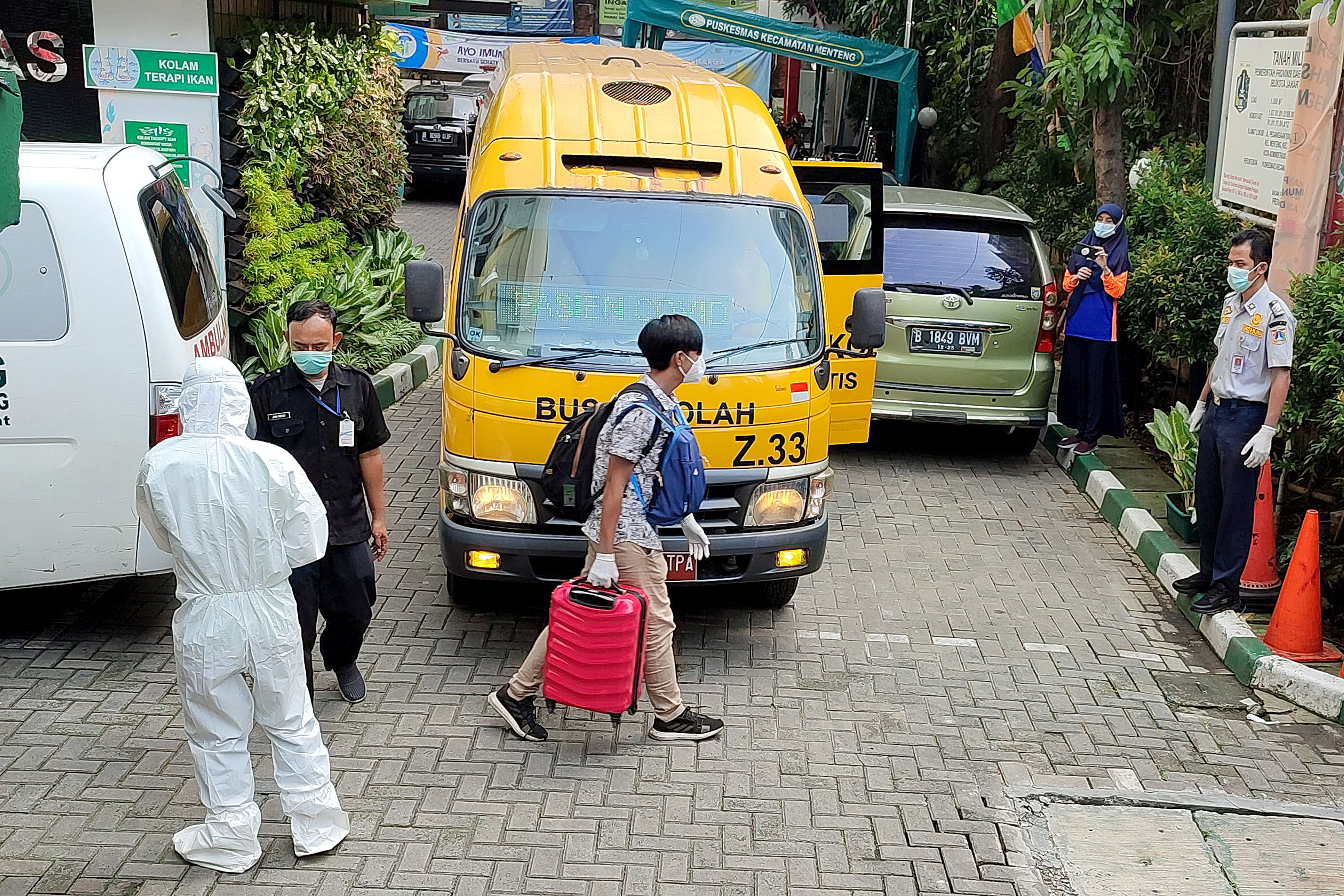 Pasien terindikasi positif covid-19 dibawa menggunakan bus sekolah di Puskesmas Kecamatan Menteng, Jakarta, Minggu (20/6).
