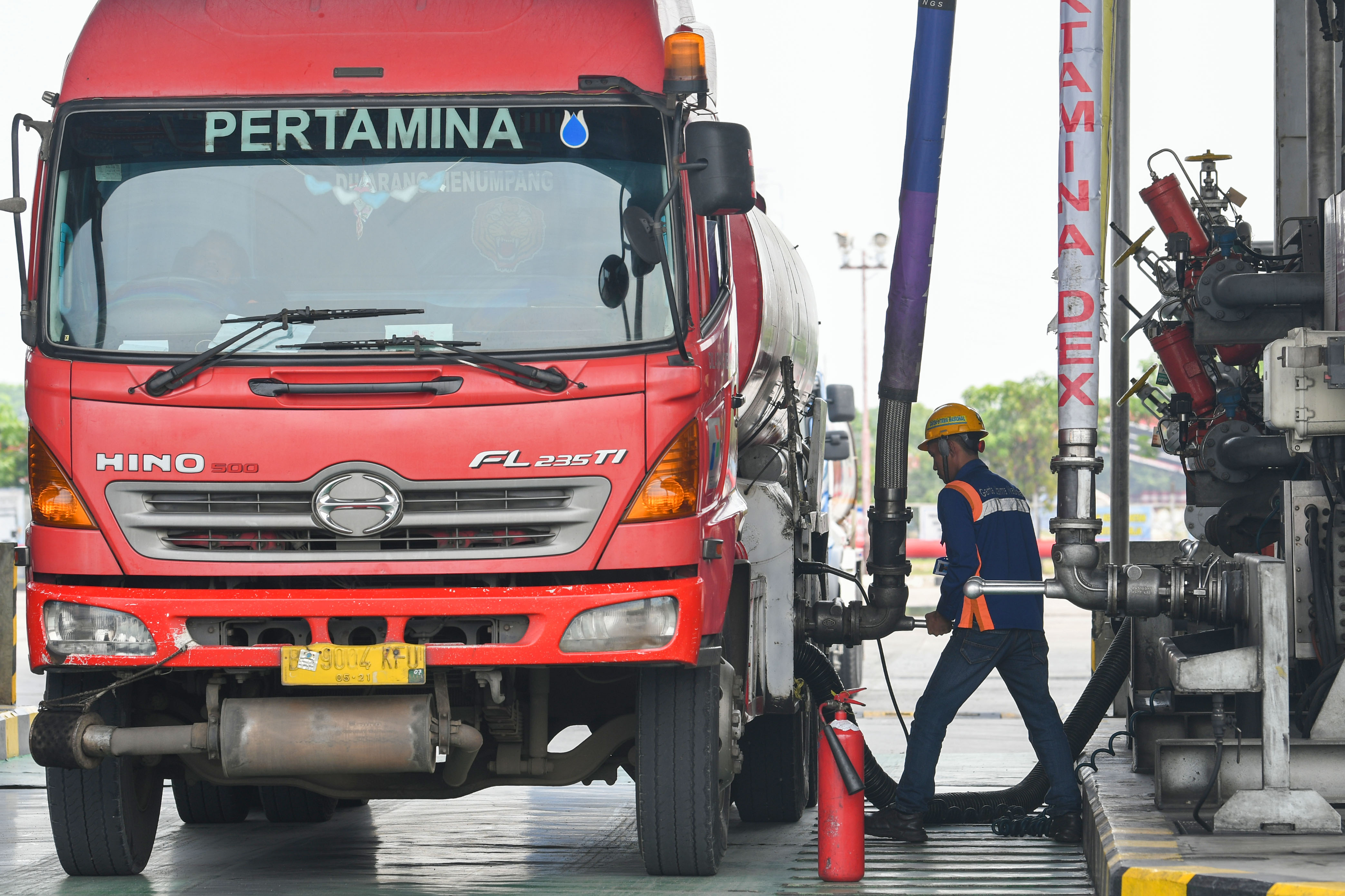 Ilustrasi petugas mengisi BBM ke mobil tangki di area pengisian otomatis.