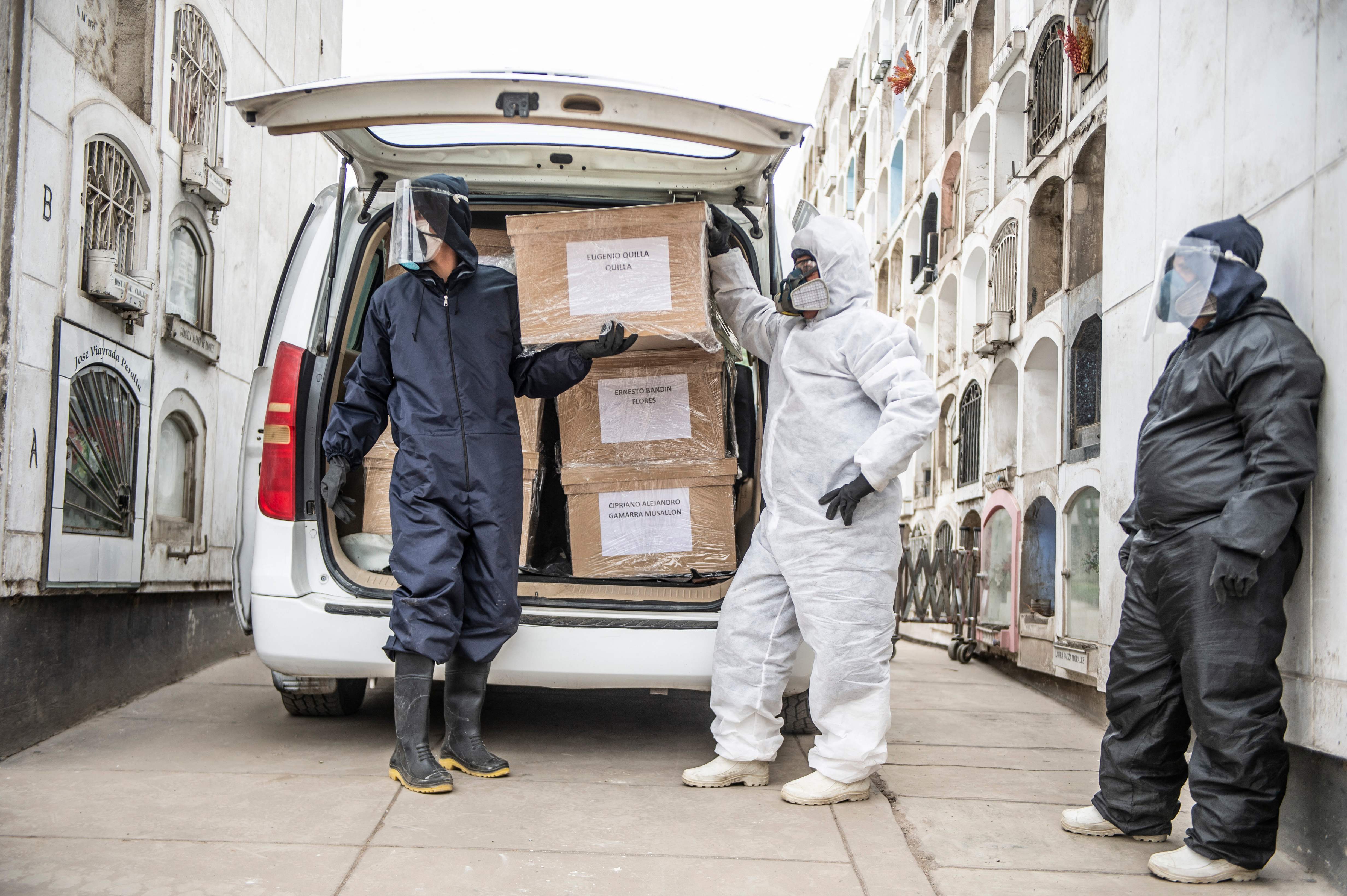 Petugas berdiri di dekat kendaraan yang membawa peti mati korban Covid-19 di Kot Lima, Peru, Senin (31/5).