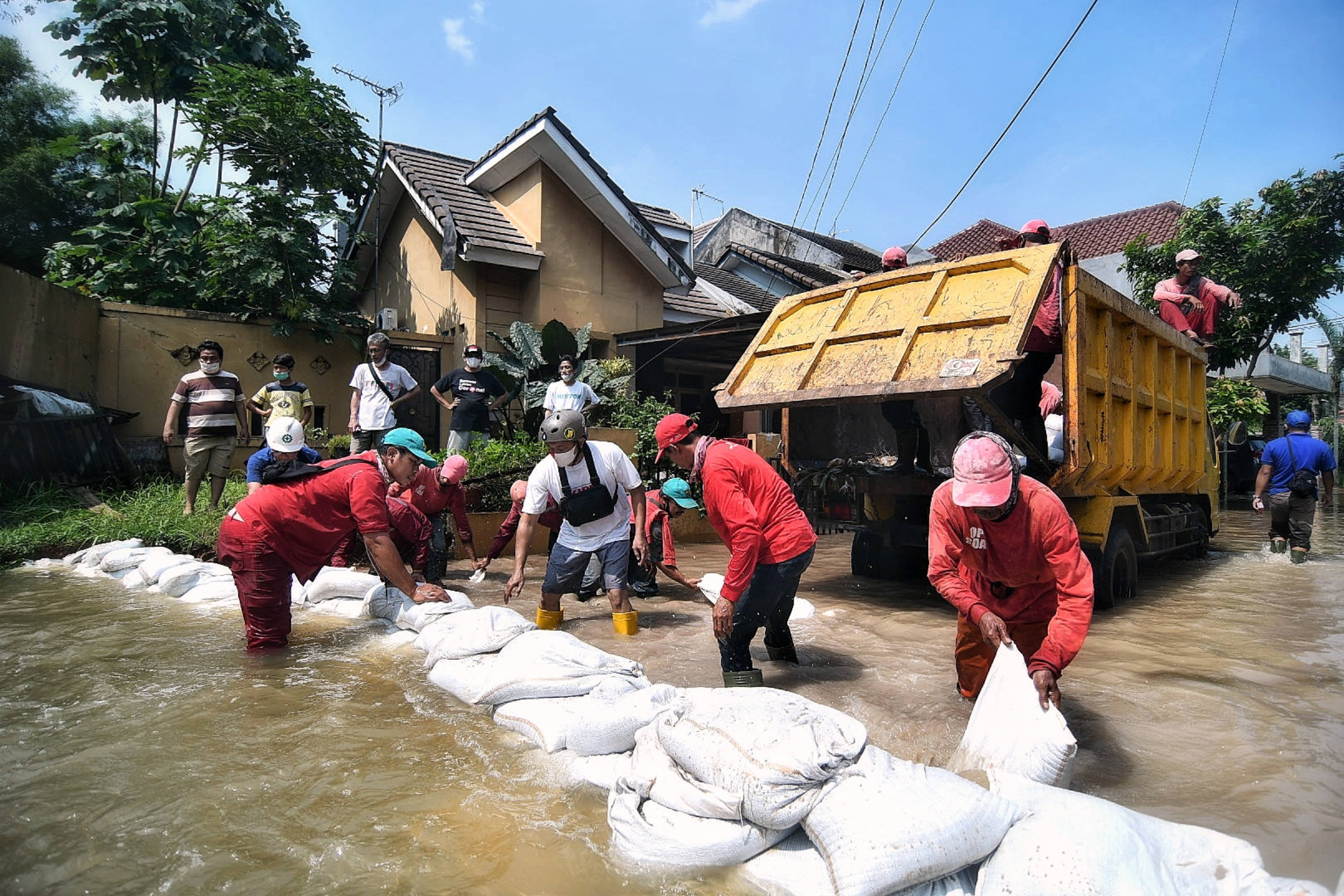 Petugas membuat tanggul sementara untuk menahan luapan air sungai di Tangerang Selatan.