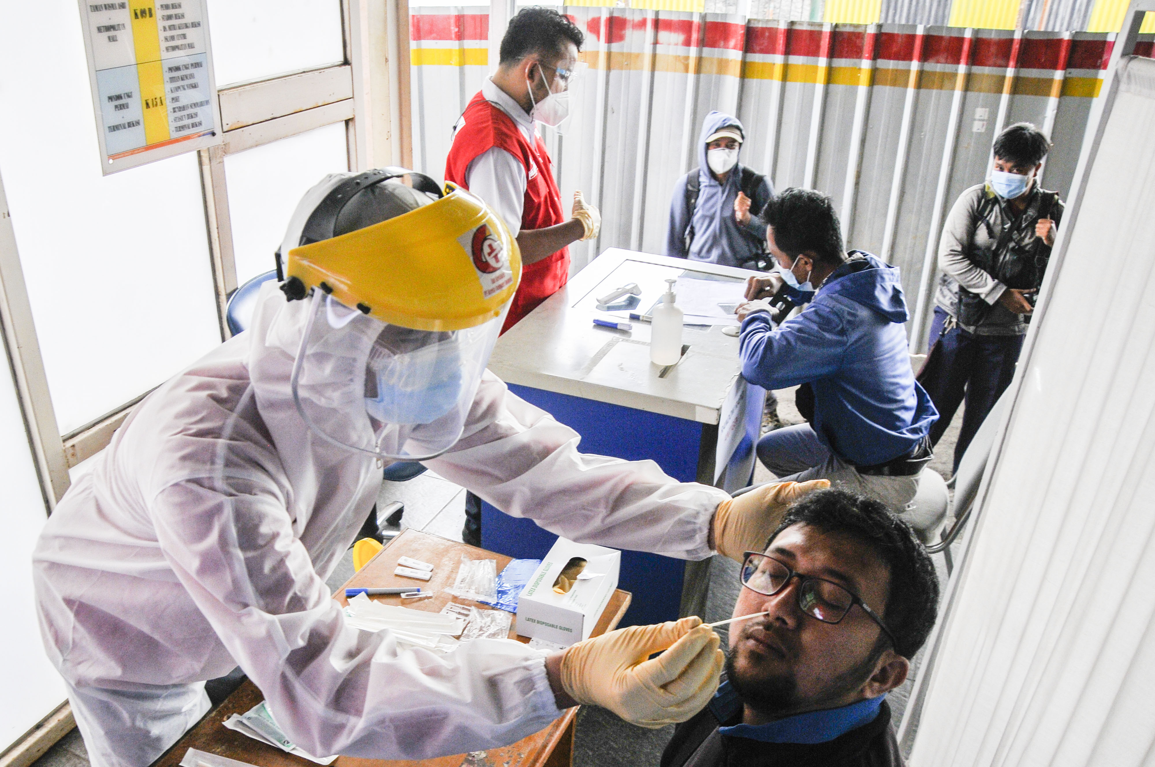 Petugas medis (kiri) melakukan tes usap antigen kepada calon penumpang KRL (Kereta Rel Listrik) di Stasiun Bekasi, Jawa Barat, Senin (21/6)