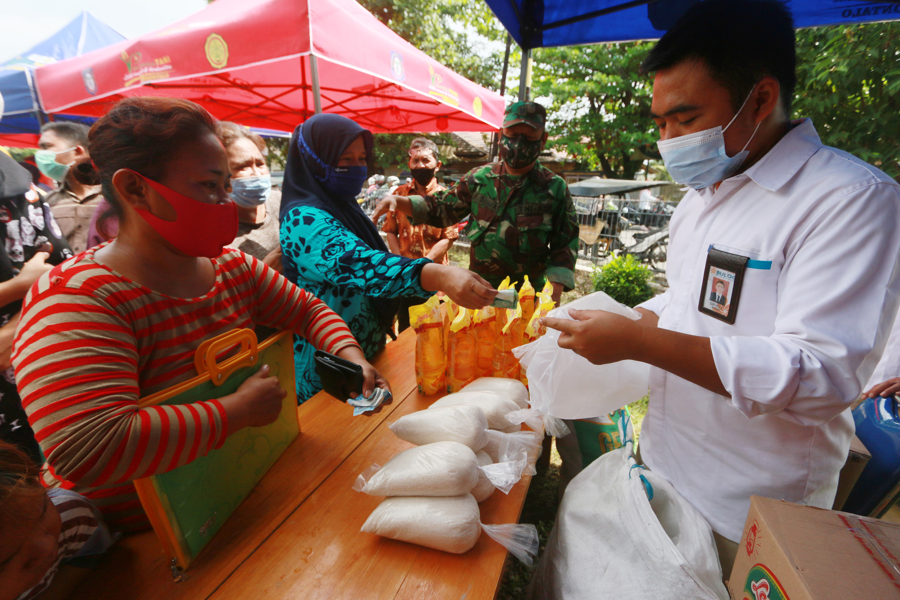Sejumlah warga antre membeli minyak goreng dan gula pasir dari lapak Bulog Subdivre Gorontalo di Pasar Mitra Tani di Kota Gorontalo, beberap