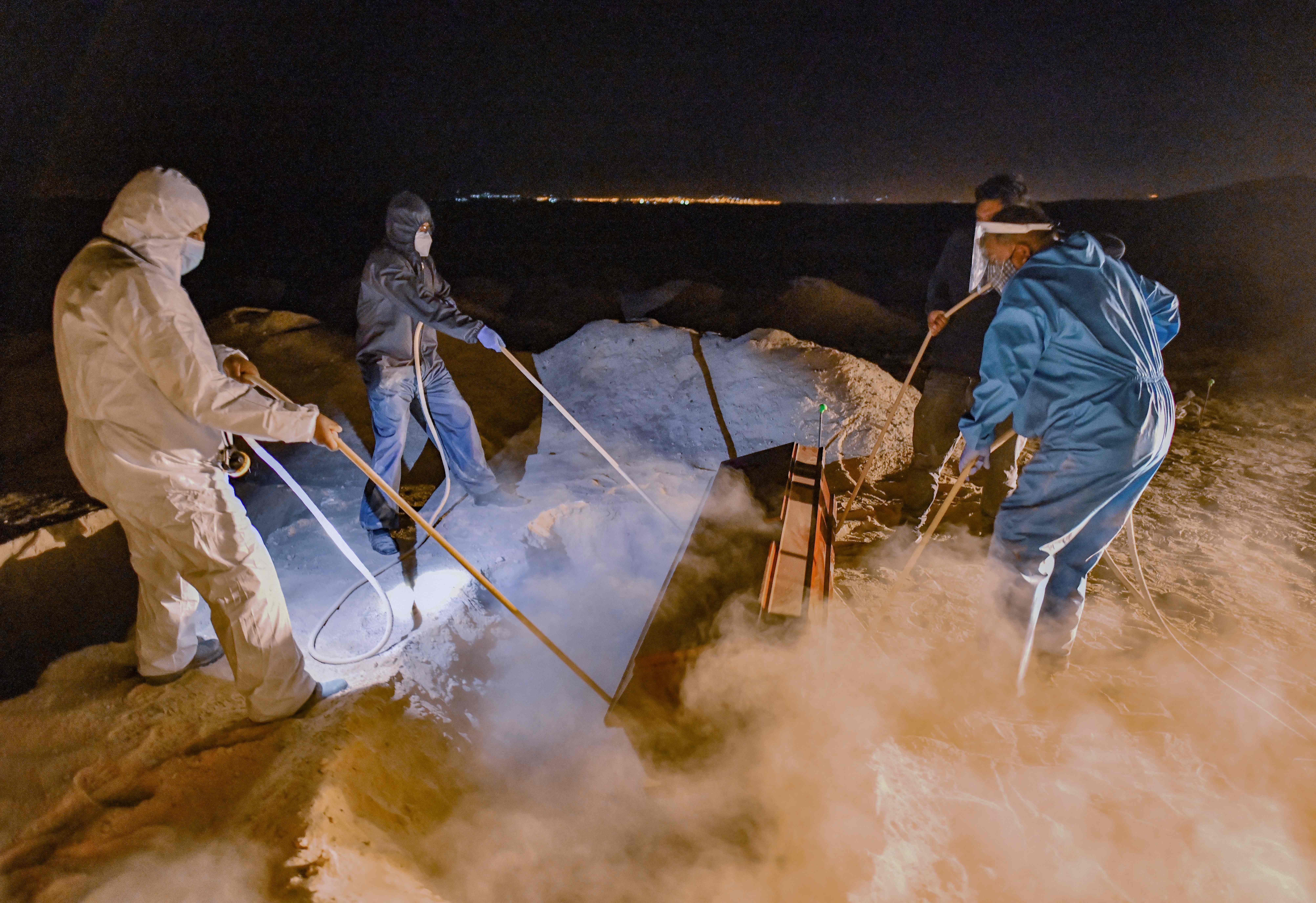 Petugas menurunkan peti jenazah pasien covid-19 ke dalam liang lahat di Kota Arequipa, Peru.