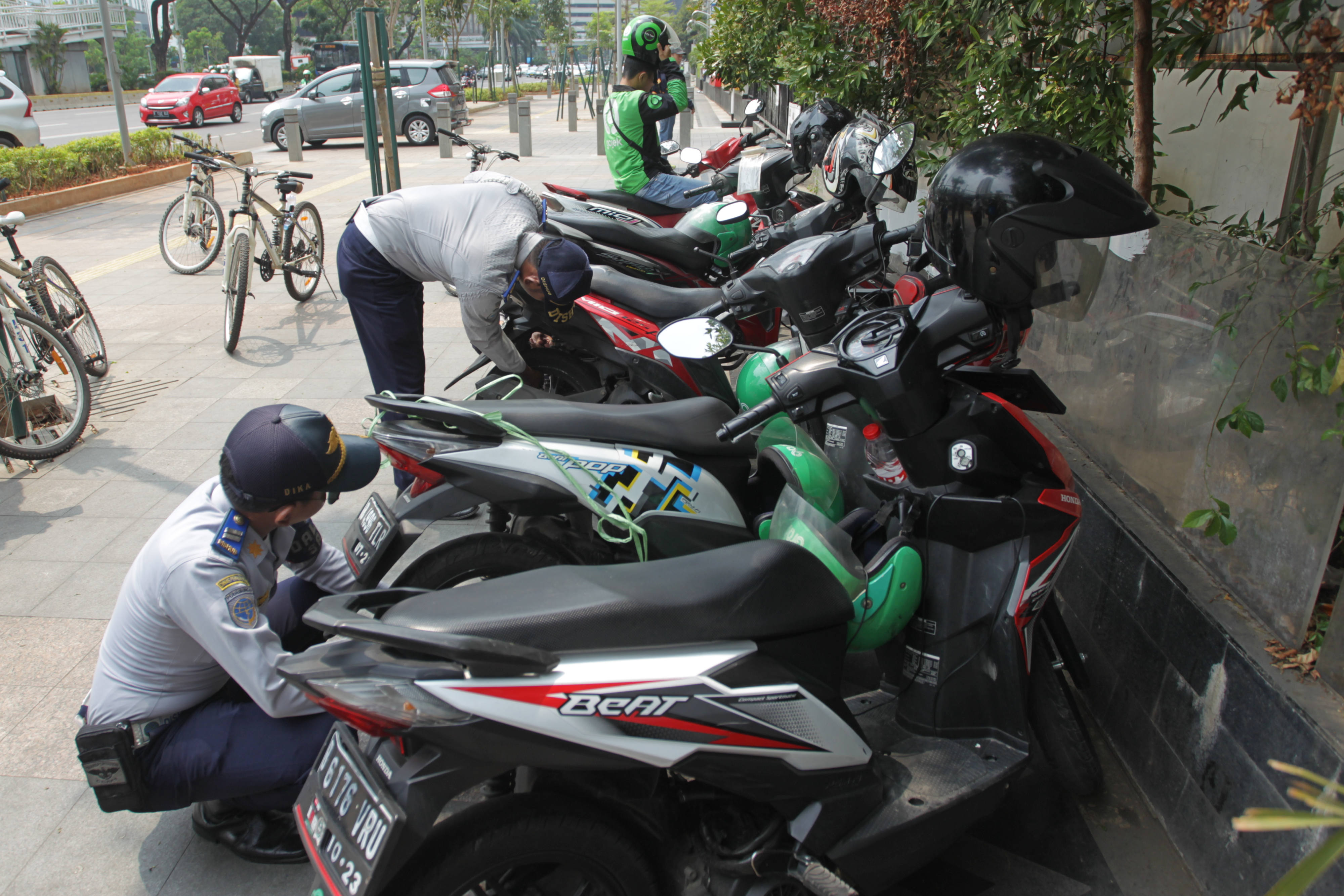 Petugas Dinas Perhubungan DKI Jakarta mencabut pentil motor yang diparkir di trotoar di kawasan Sudirman, Jakarta.
