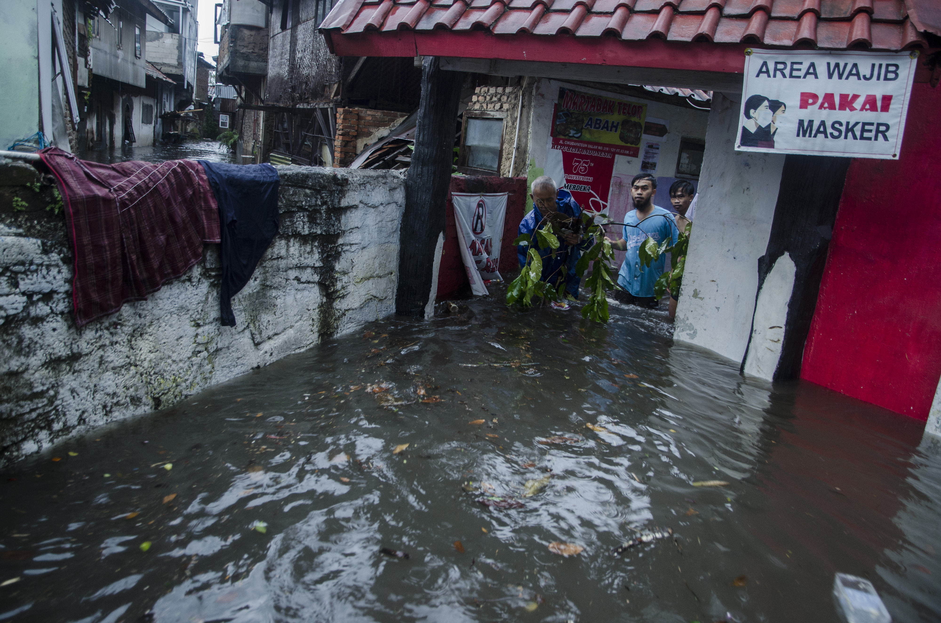 Warga membersihkan sampah yang terbawa arus banjir di kawasan Kacapiring, Bandung, Jawa Barat, Senin (21/6/2021).