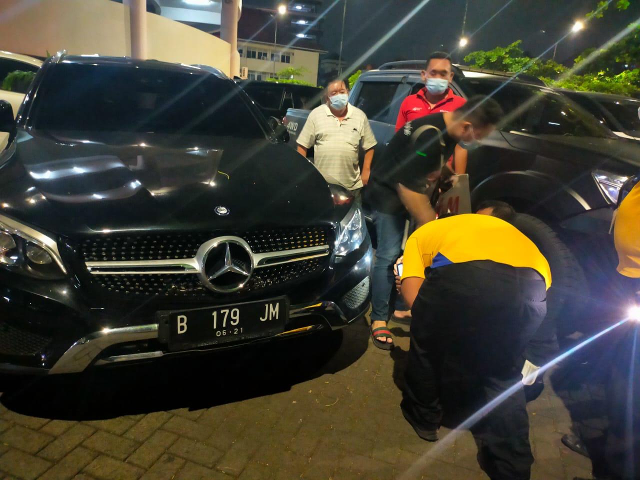 Petugas parkir memeriksa body mobil mercedes-benz yang dituduh diserempet, ternyata tidak ada yang lecet.