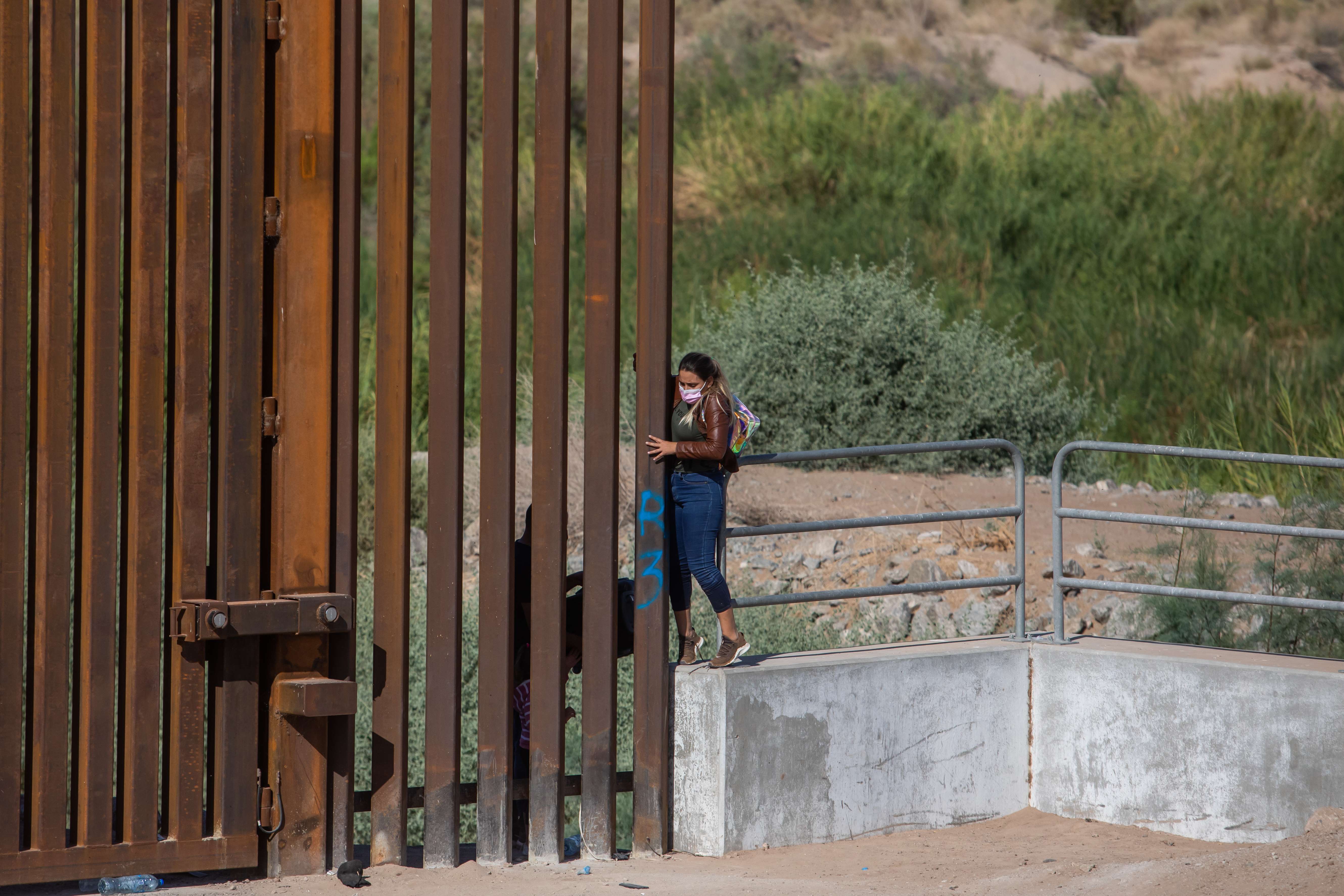 Seorang imigran melintasi bagian yang terbuka di tembok perbatasan antara Amerika Serikat dan Meksiko.