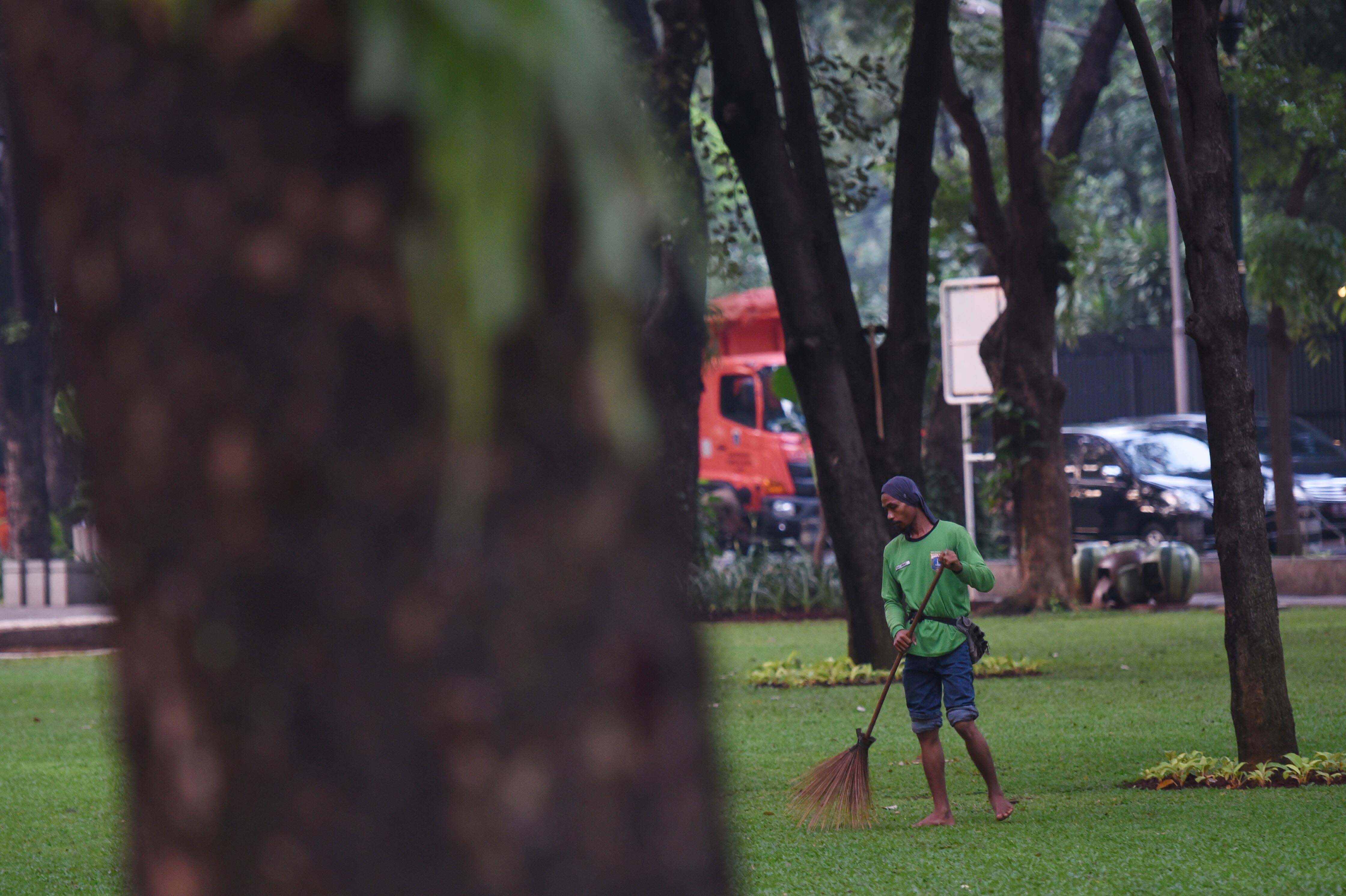 Pekerja harian lepas kebersihan menyapu Taman Suropati di Jakarta, yang ditutup untuk umum hingga 5 Juli 2021.