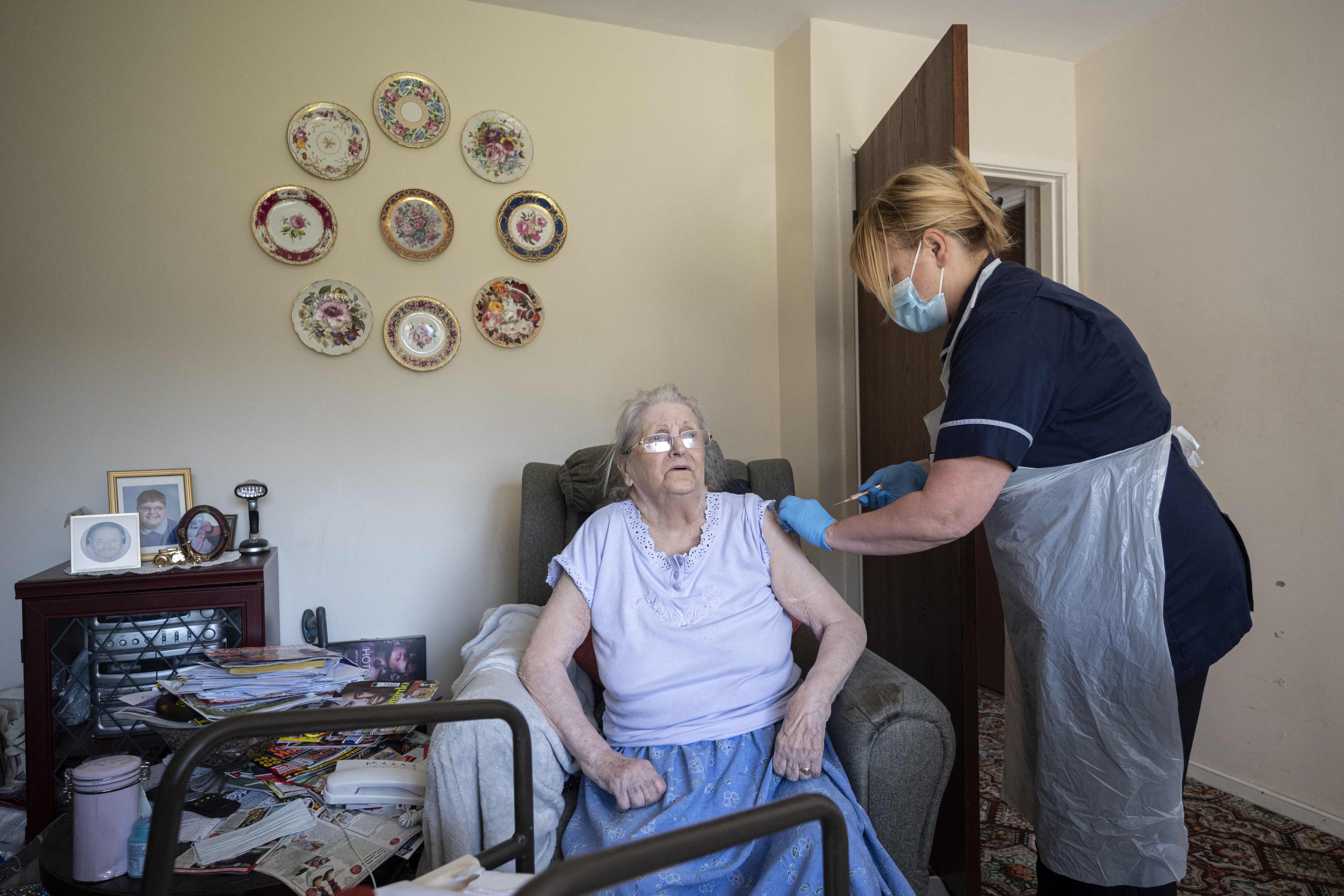 Pekerja panti jompo menyuntikan vaksin covid-19 kepada seorang penghuni di Chesterfield, Inggris.