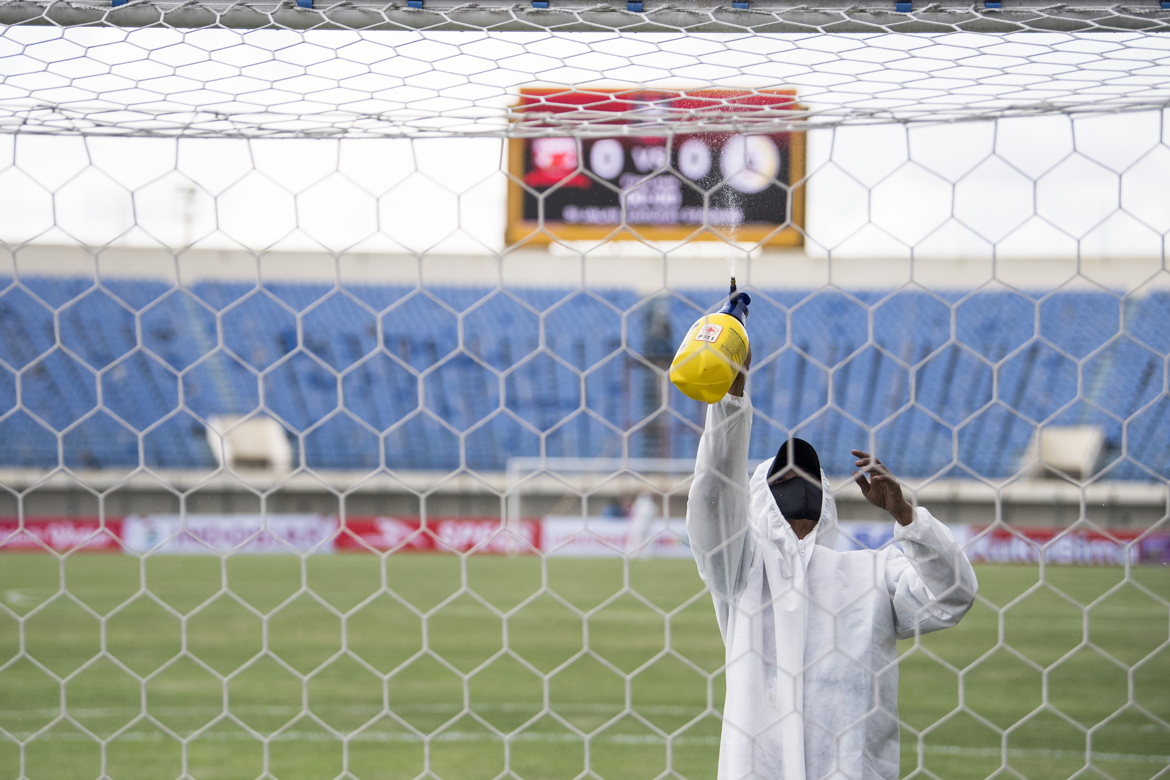 Petugas menyemprotkan cairan disinfektan ke tiang gawang di Stadion Si Jalak Harupat, Jawa Barat.