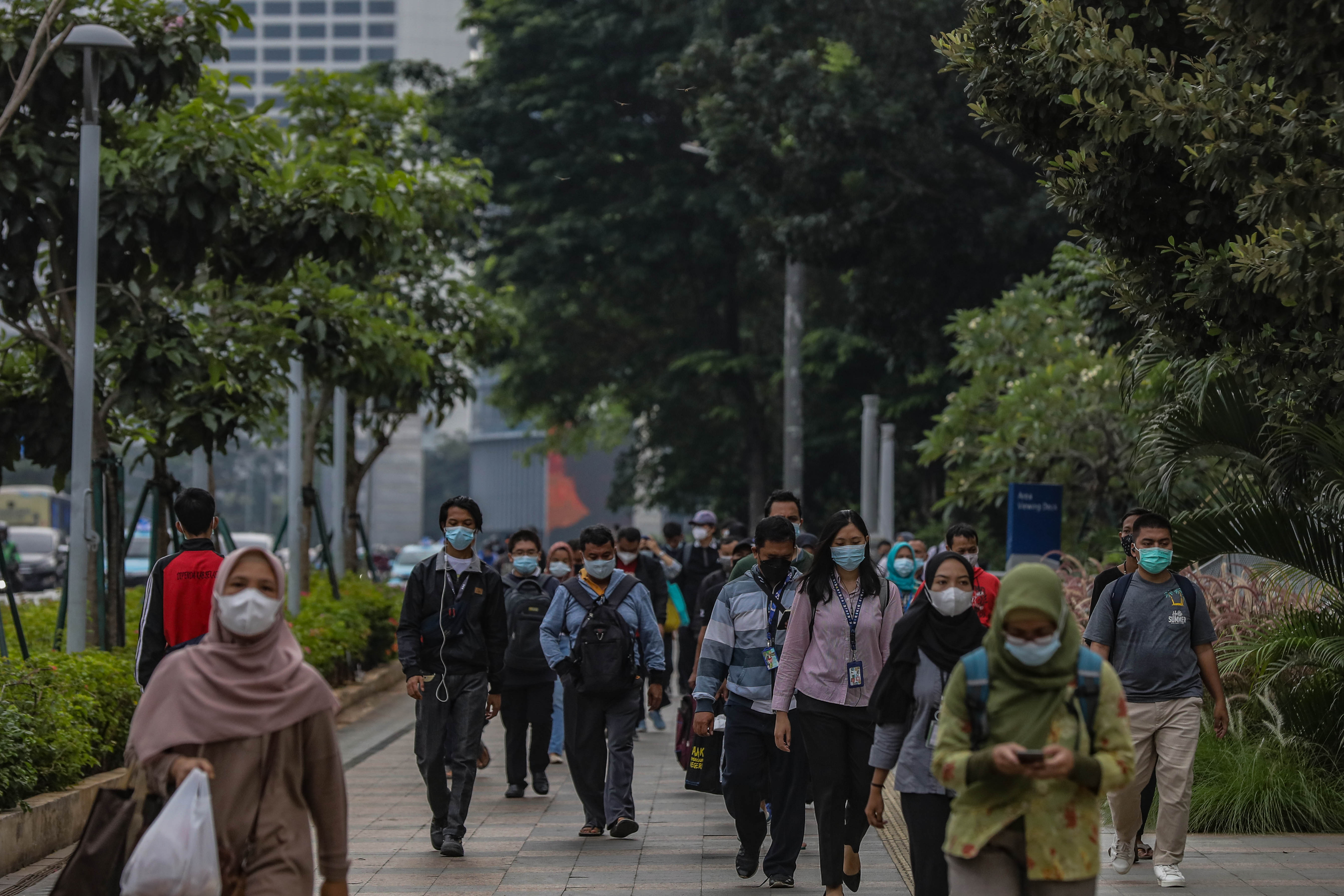 Sejumlah pekerja melintasi trotoar di kawasan Sudirman, Jakarta.